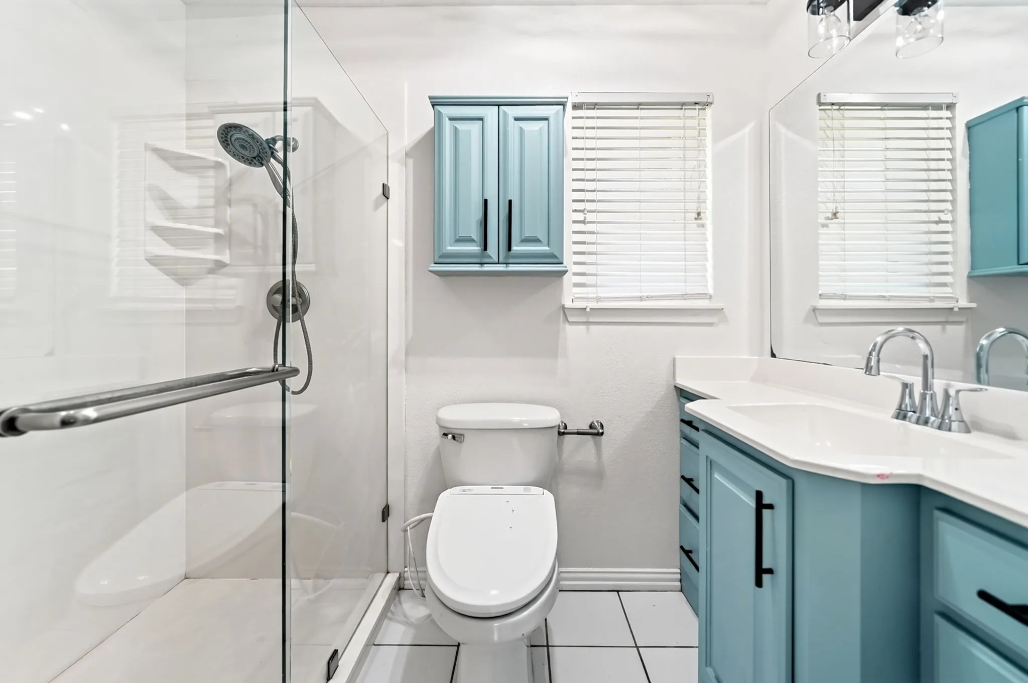 Glass-enclosed shower with handheld shower fixture and built-in shelving