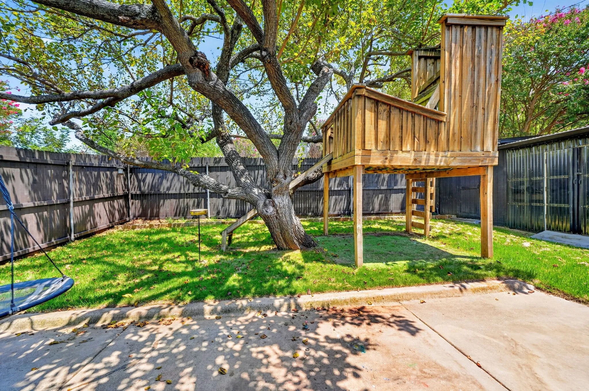 Expansive backyard featuring a mature tree, manicured lawn, and privacy fencing