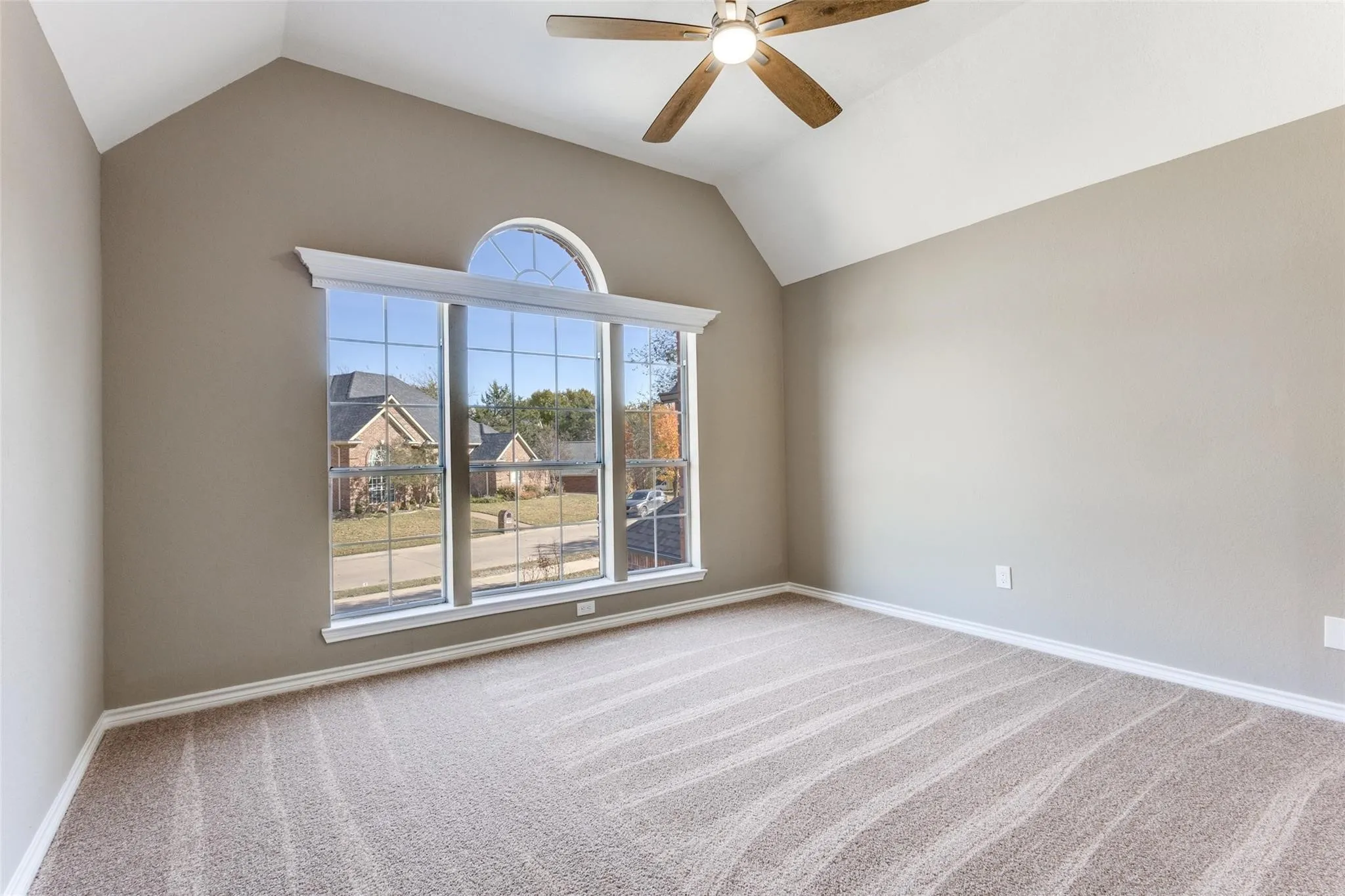 Bedroom upstairs has vaulted ceiling, ceiling fan, arched window with transom, and NEW neutral carpeting