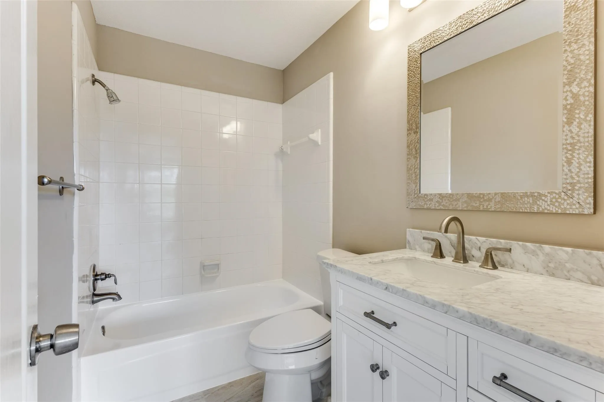2nd full bath updstairs with stone countertop, bronze-finish faucet, and an ornate framed mirror