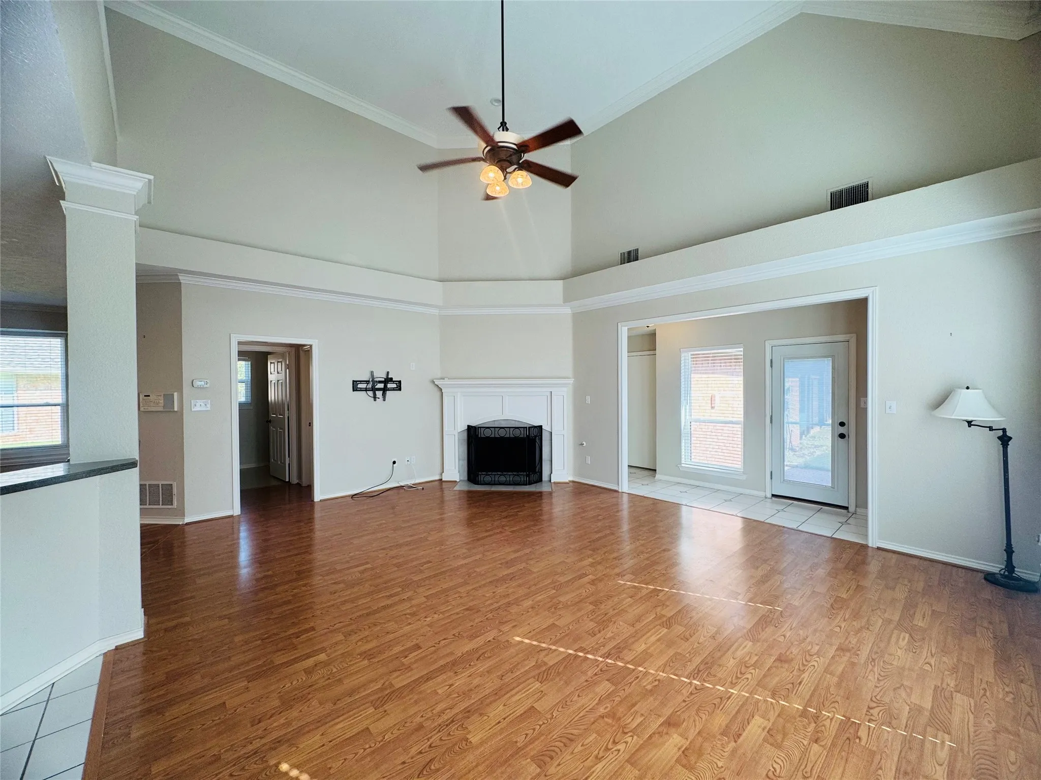 Vaulted ceilings, wood-finish flooring, white mantel, and a ceiling fan with integrated lighting