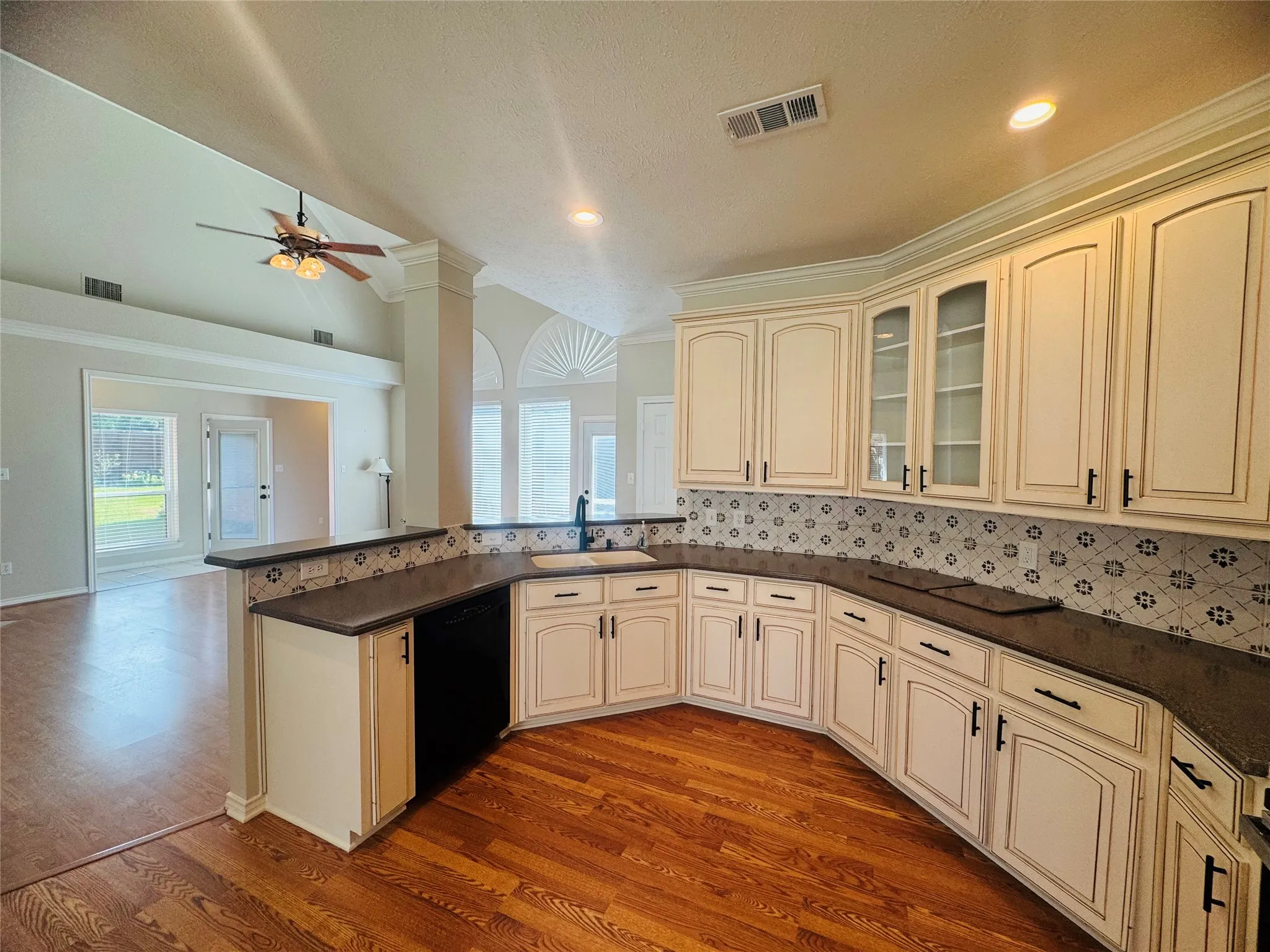 Kitchen with light-toned cabinetry, dark countertops, and a patterned backsplash