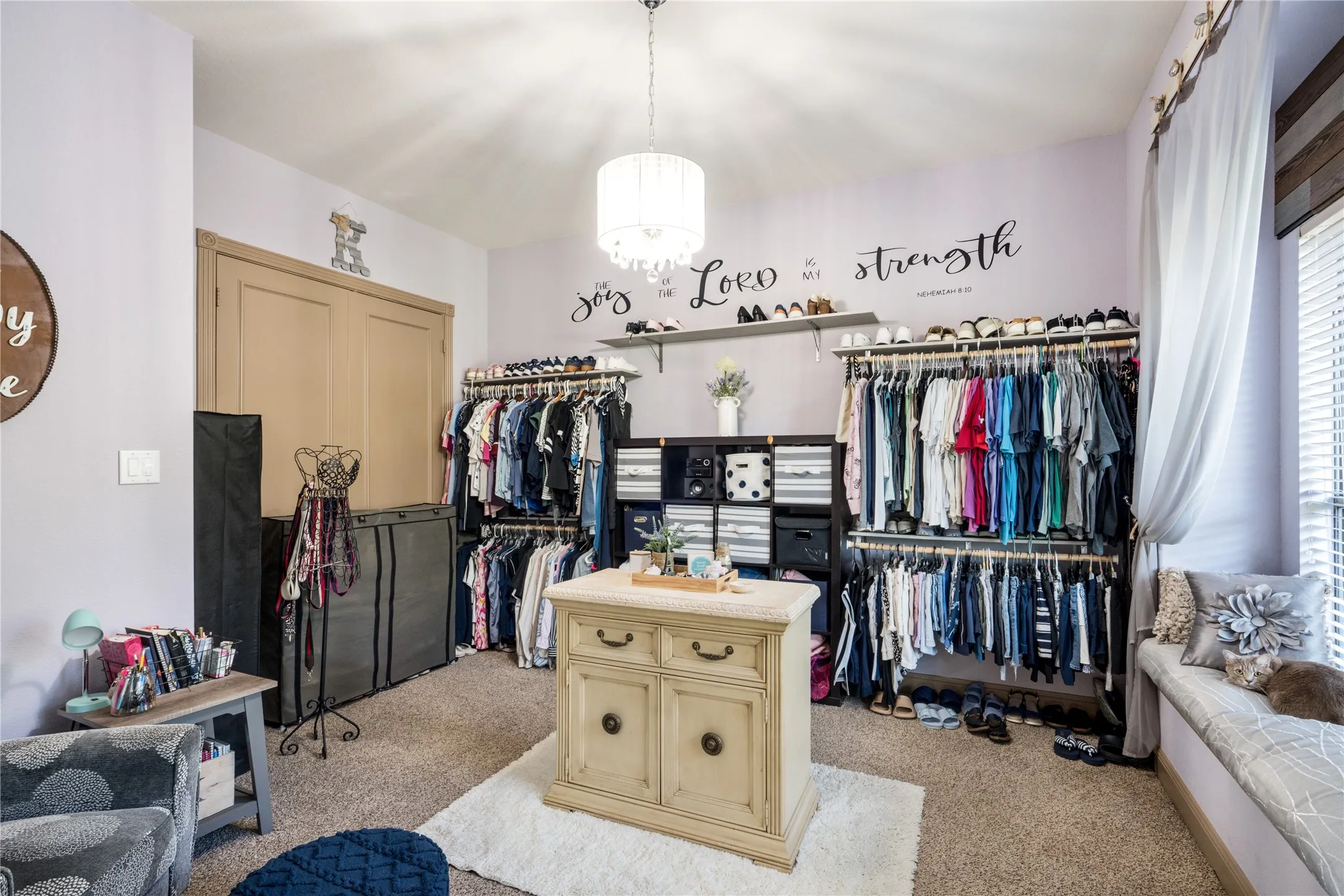 Built-in window bench, extensive shelving, built-in clothing racks, ceiling-mounted light fixture, and broad window
