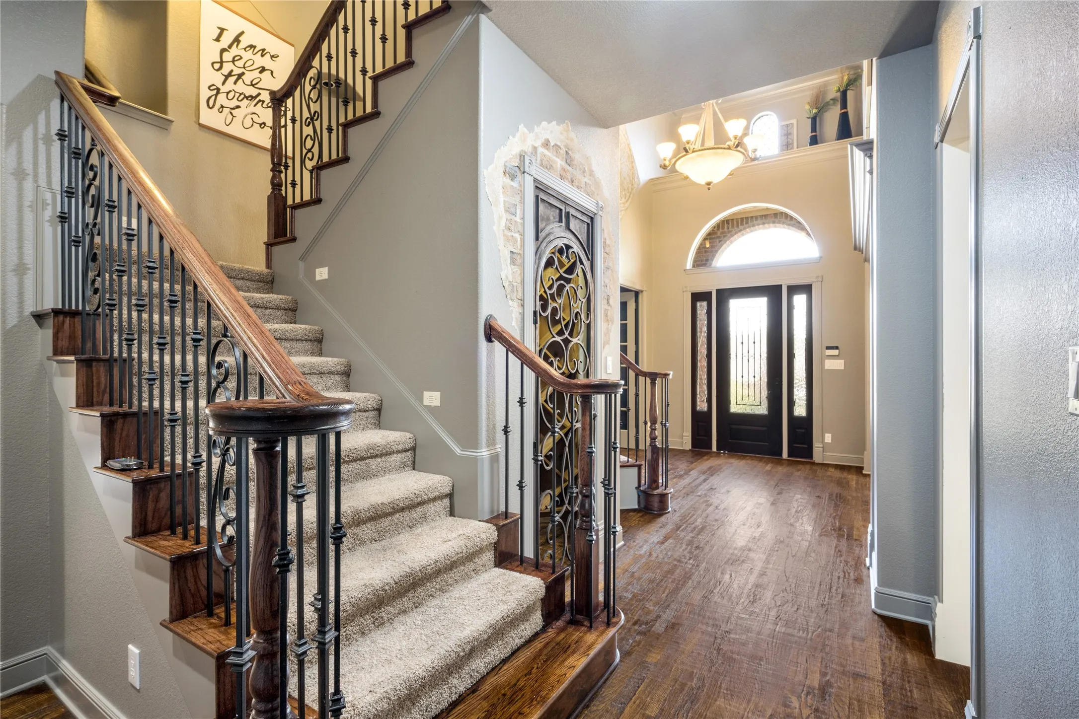 Grand entry featuring rich wood-finish flooring, a two-story ceiling, and a chandelier