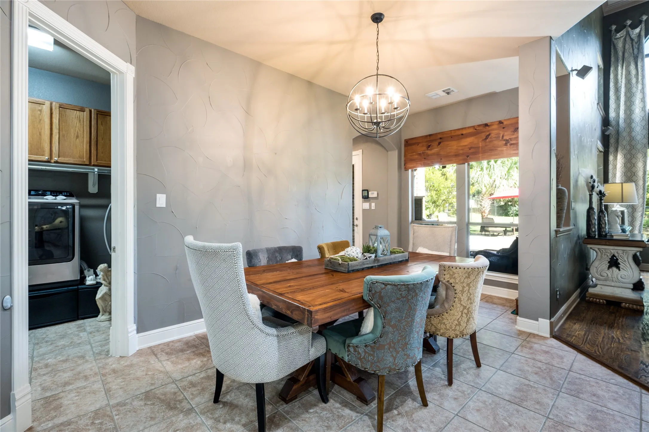 Dining area with a wood-finish table, tile flooring, and a contemporary spherical chandelier