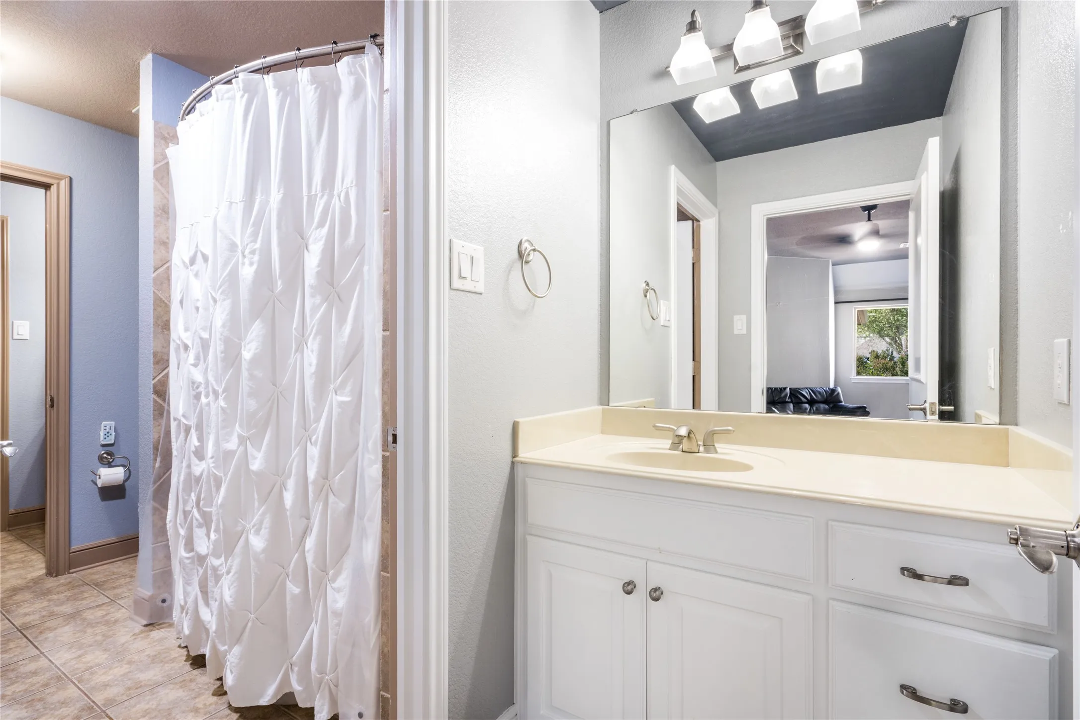 Bathroom featuring a single vanity with an integrated sink, white cabinetry, and brushed nickel hardware