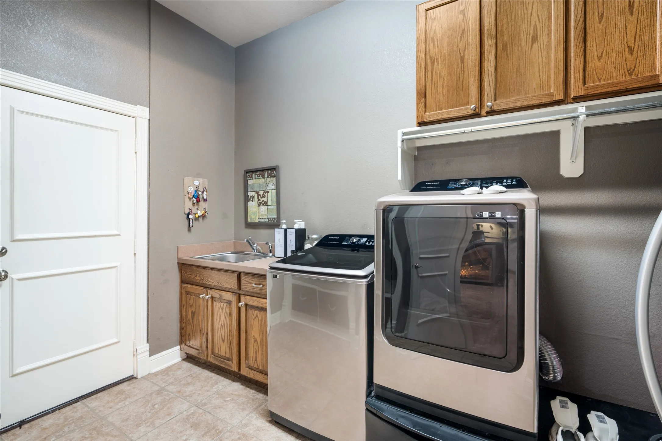 Laundry area featuring wood cabinetry, a utility sink, and tile flooring