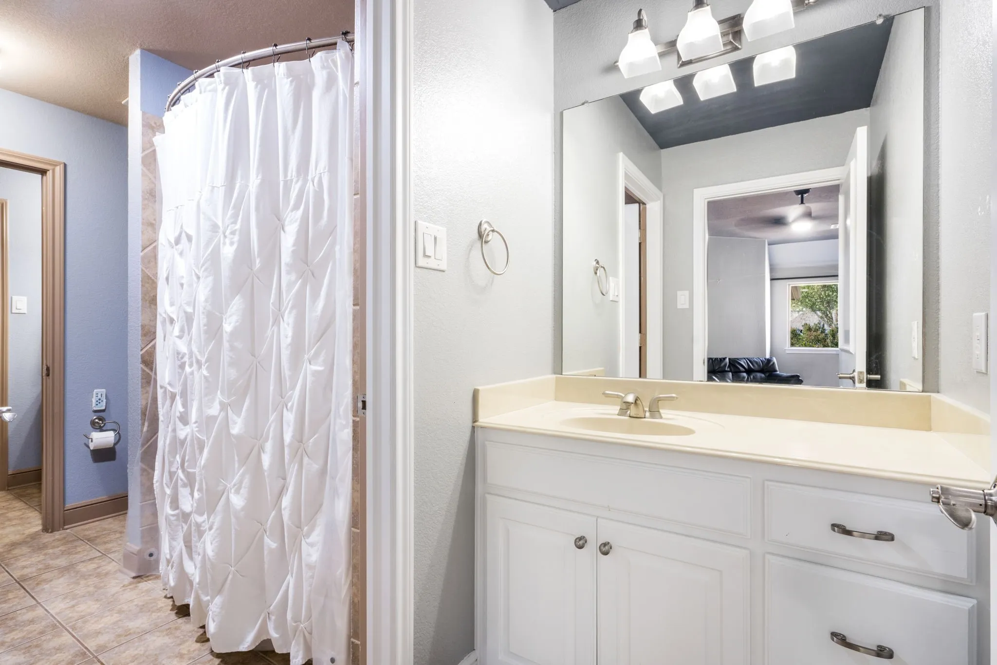 Vanity with a light-colored countertop, white cabinetry with silver-tone hardware, and an attached mirror
