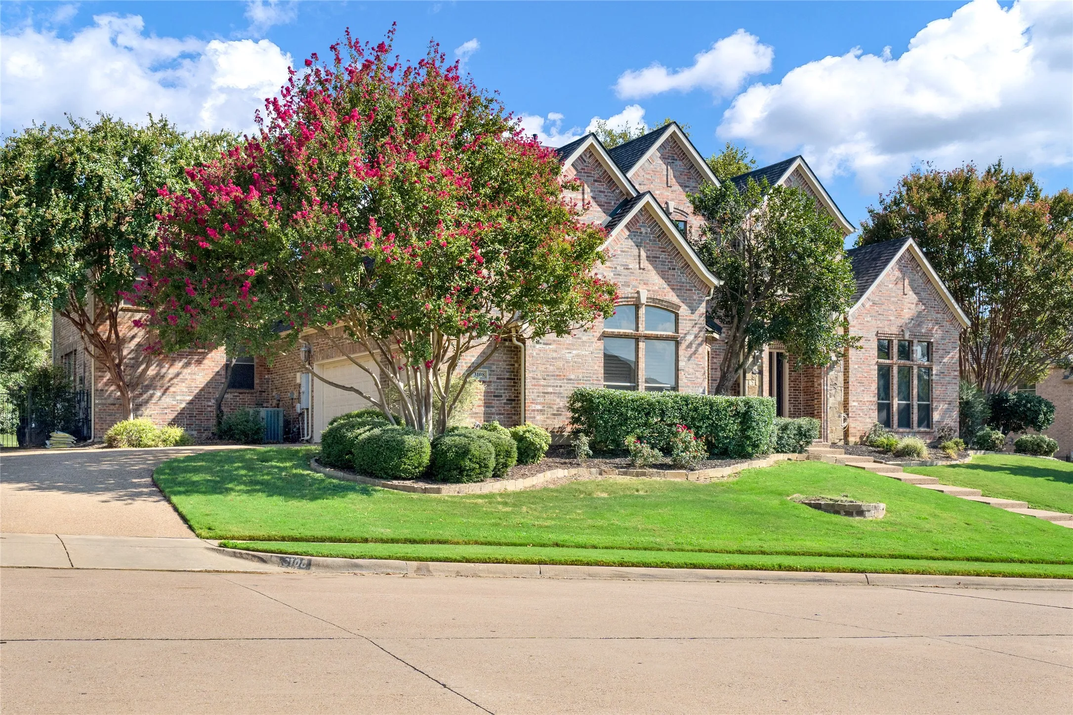 Brick exterior with multiple gabled rooflines, arched window, and a concrete driveway