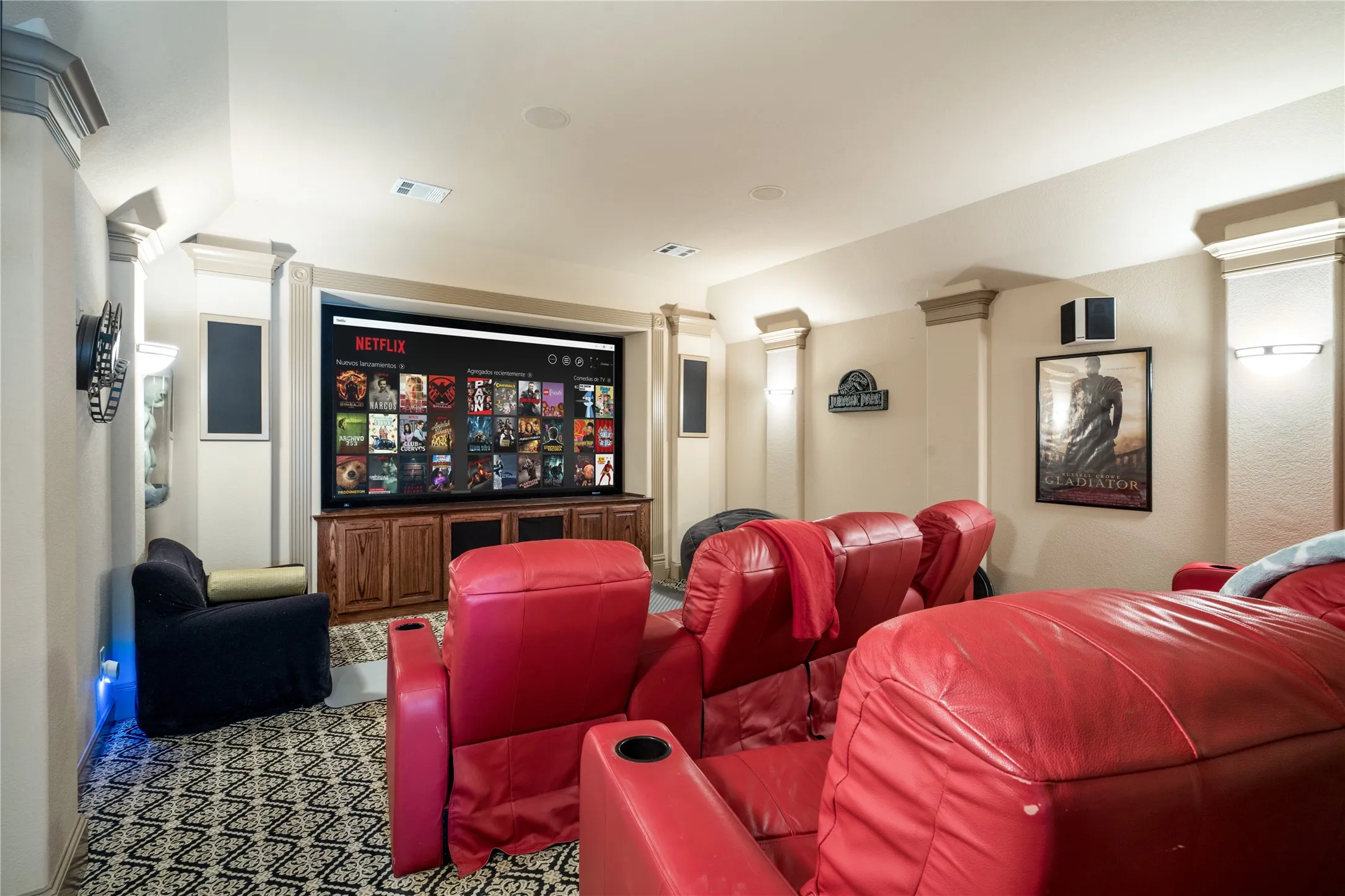 Dedicated media room featuring a large projection screen, built-in wooden media console, wall-mounted speakers, and recessed ceiling lighting