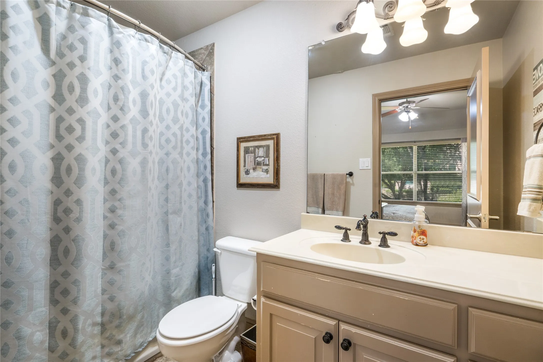 Vanity with an integrated sink, dark bronze-finish faucet, and a large mirror