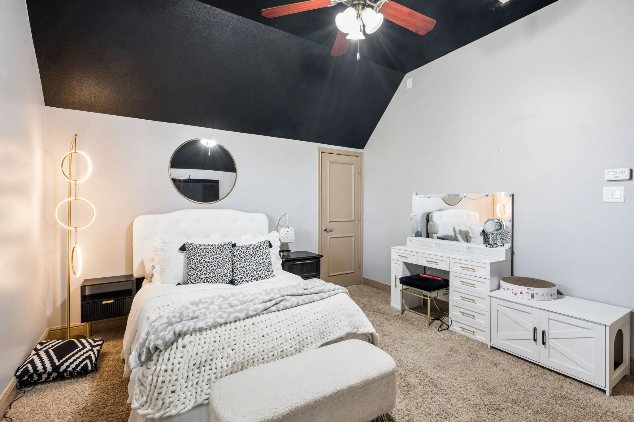 Vaulted ceiling with an attached ceiling fan, carpeted flooring, and a solid core door