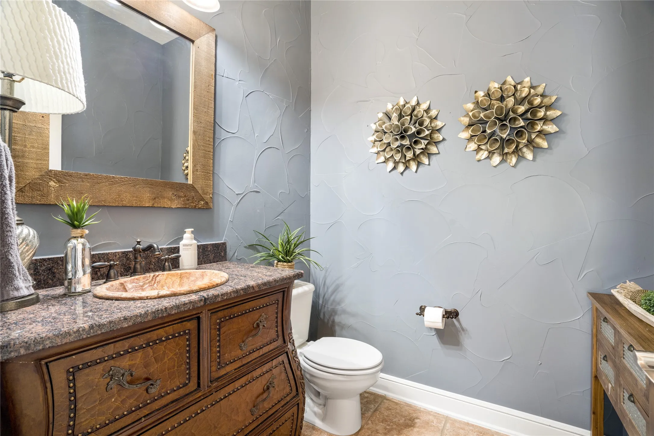 Custom vanity with a vessel sink, dark countertop, and decorative mirror