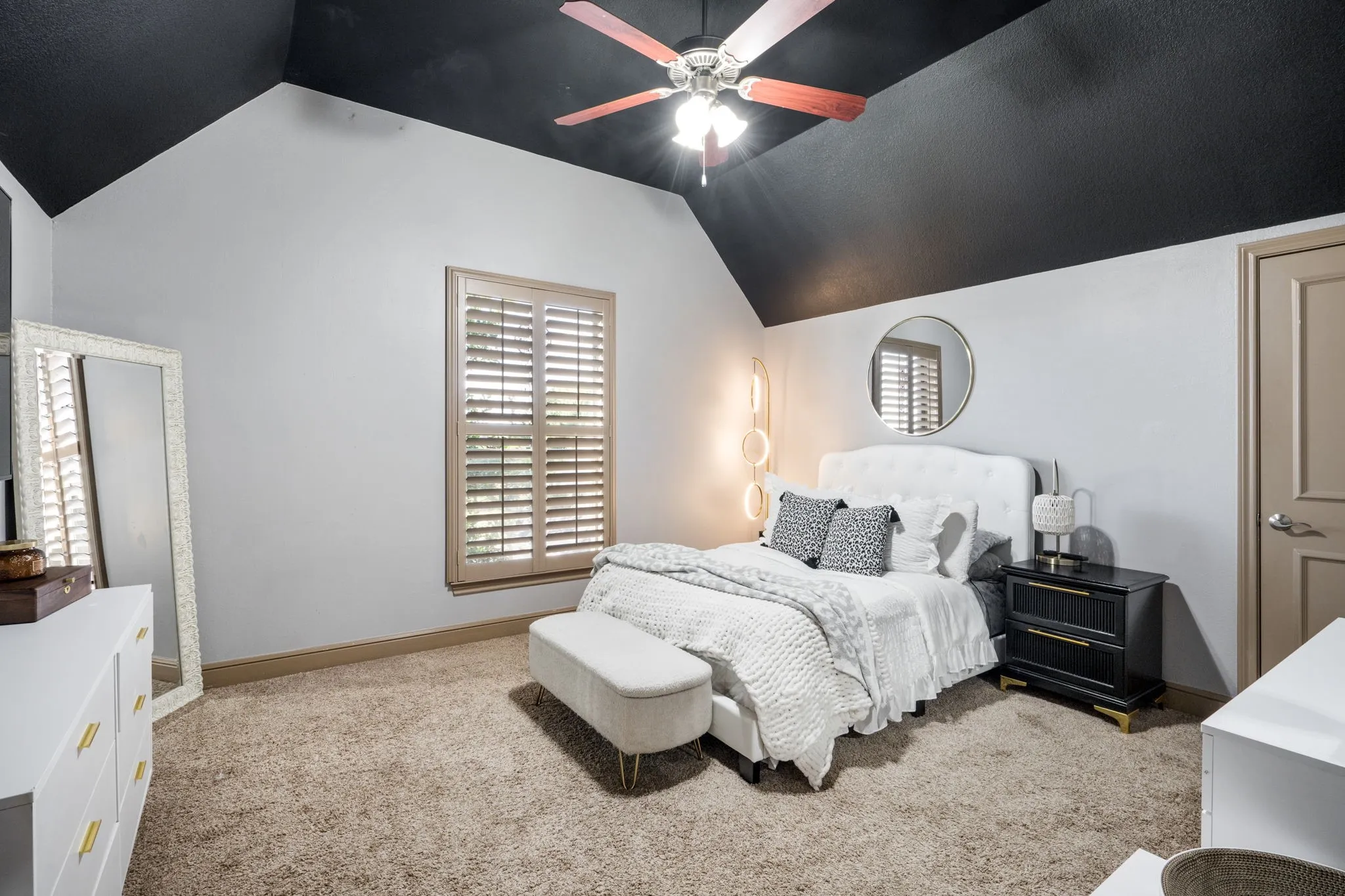 Vaulted ceiling with a ceiling fan, carpeted flooring, wood-finish window shutters, and a paneled interior door
