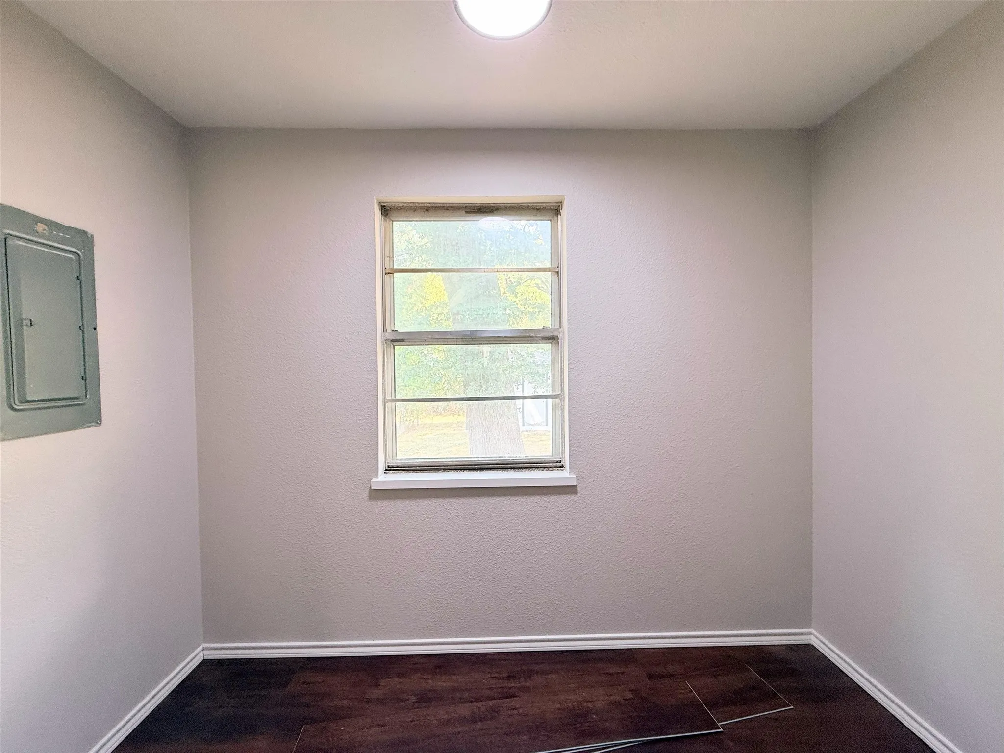 Recessed window, dark wood-finish flooring, light-toned walls, and ceiling-mounted light fixture
