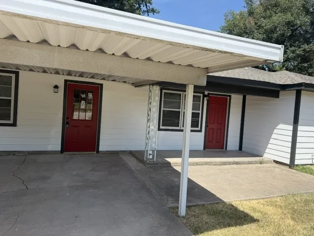 White horizontal siding exterior with two red entry doors and a carport