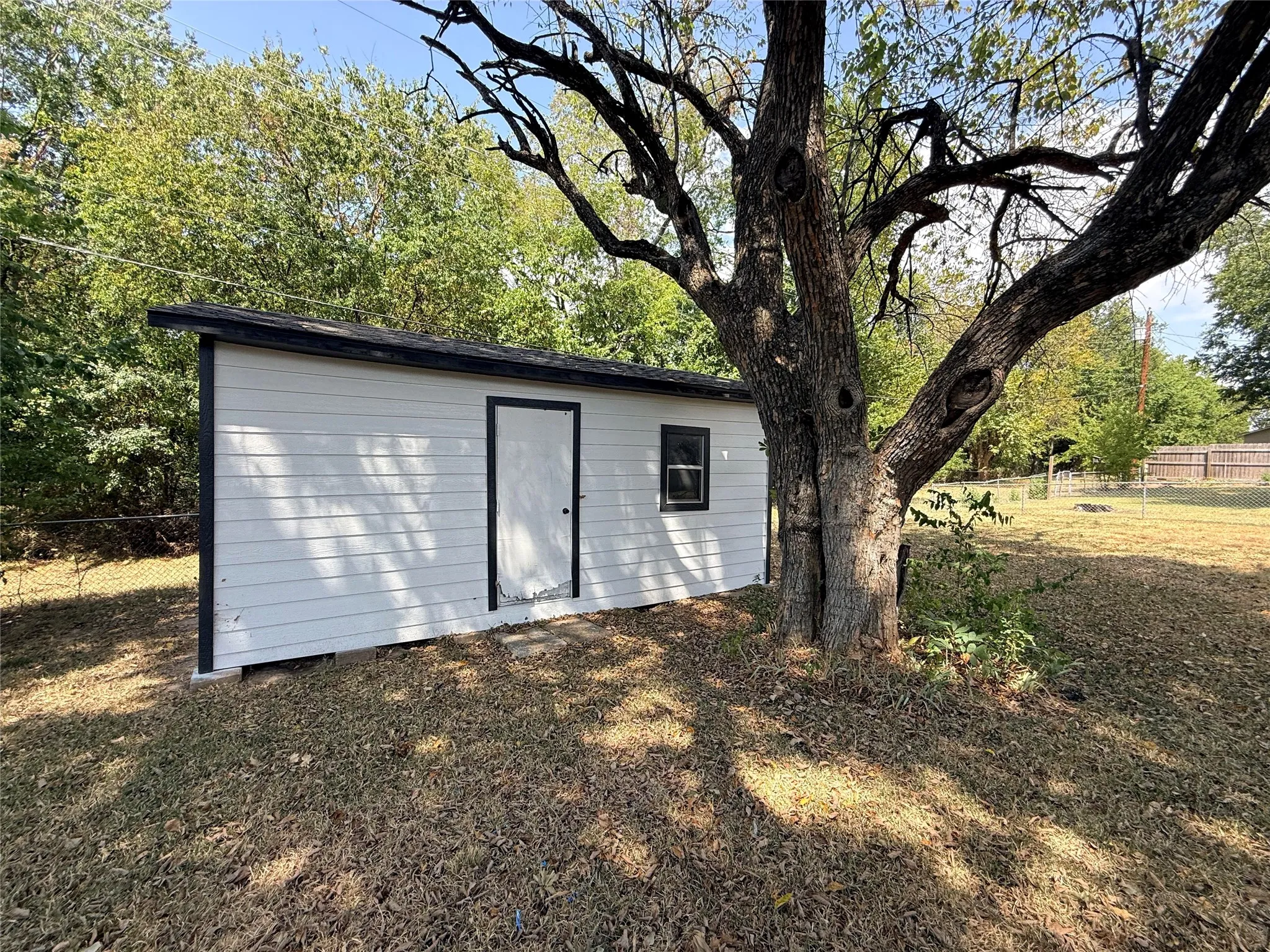 White siding utility shed with a dark trim roofline
