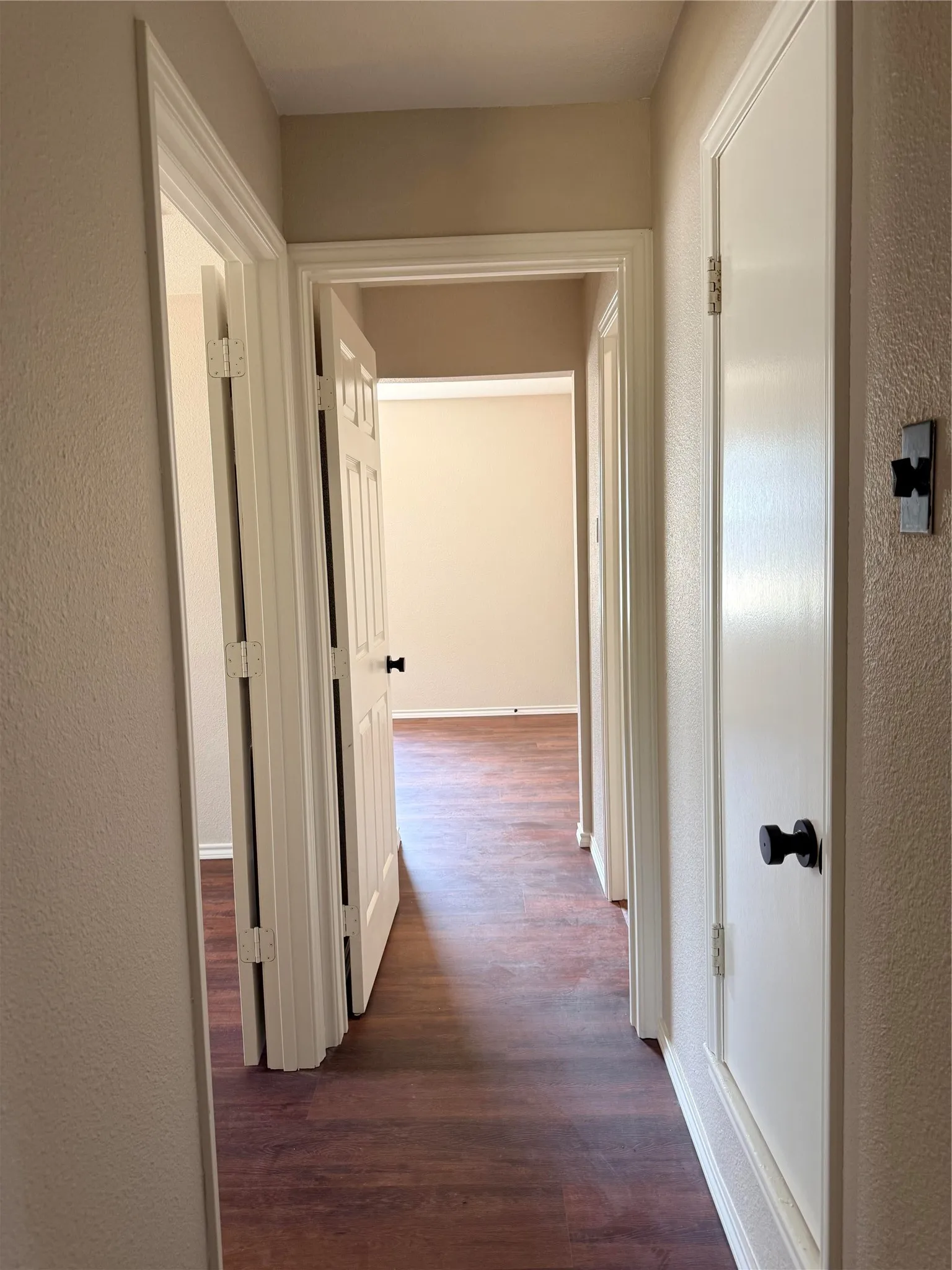 Hallway featuring wood-finish flooring, white panel doors, and neutral wall tones