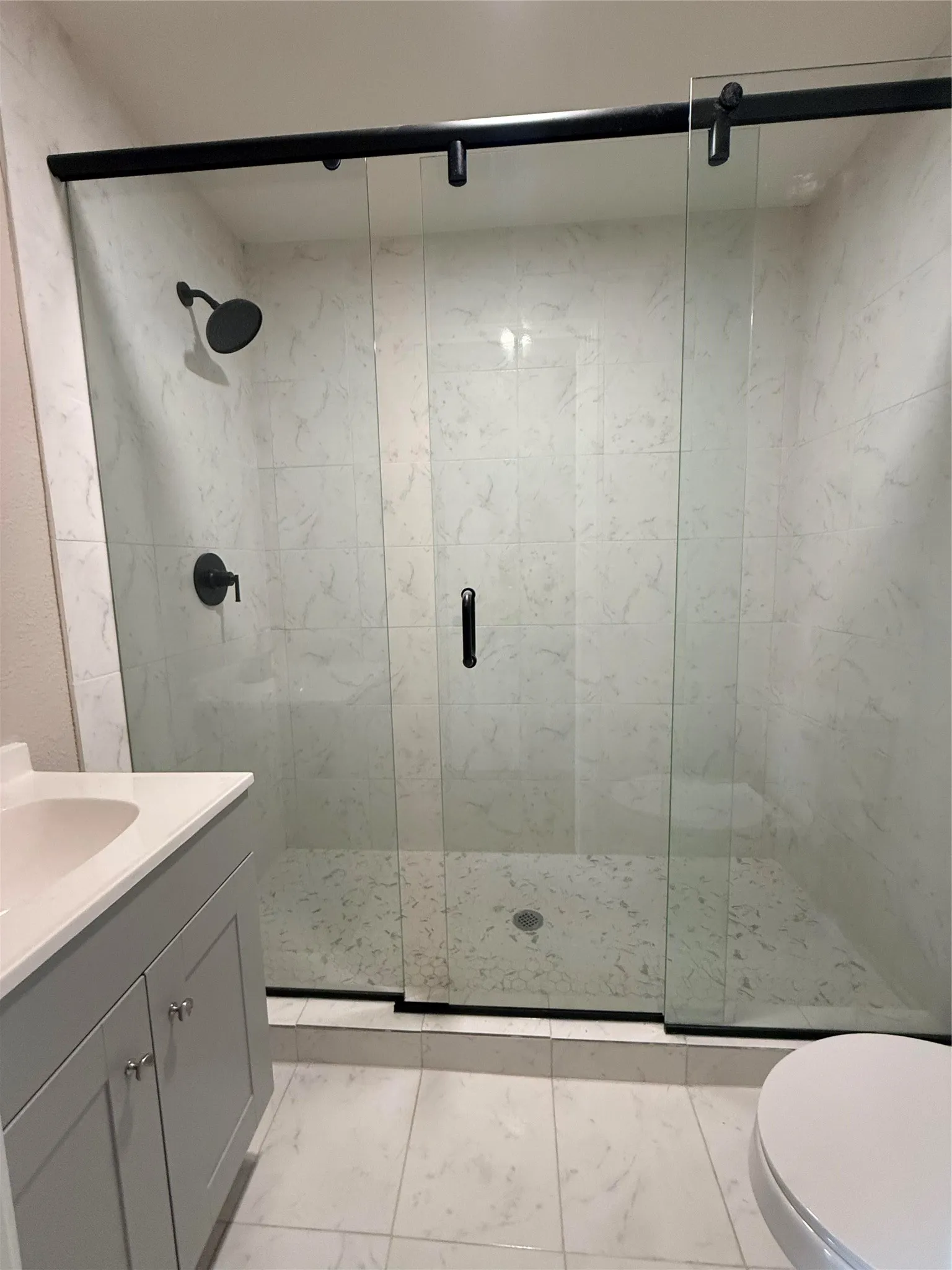 Glass-enclosed shower with matte black hardware, white tiled walls, and a tiled shower floor