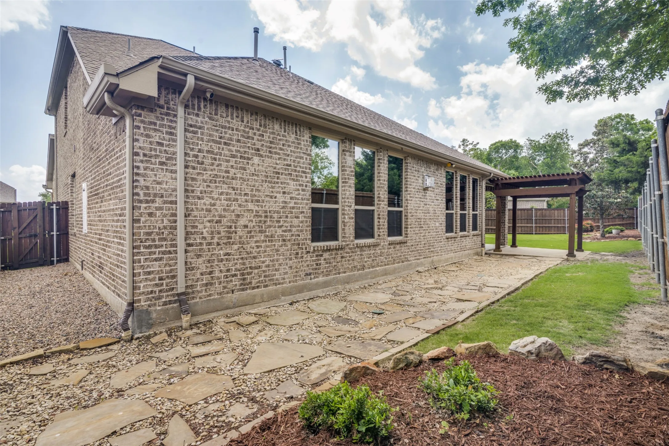 Rear of house facing patio with pergola and huge side yard.