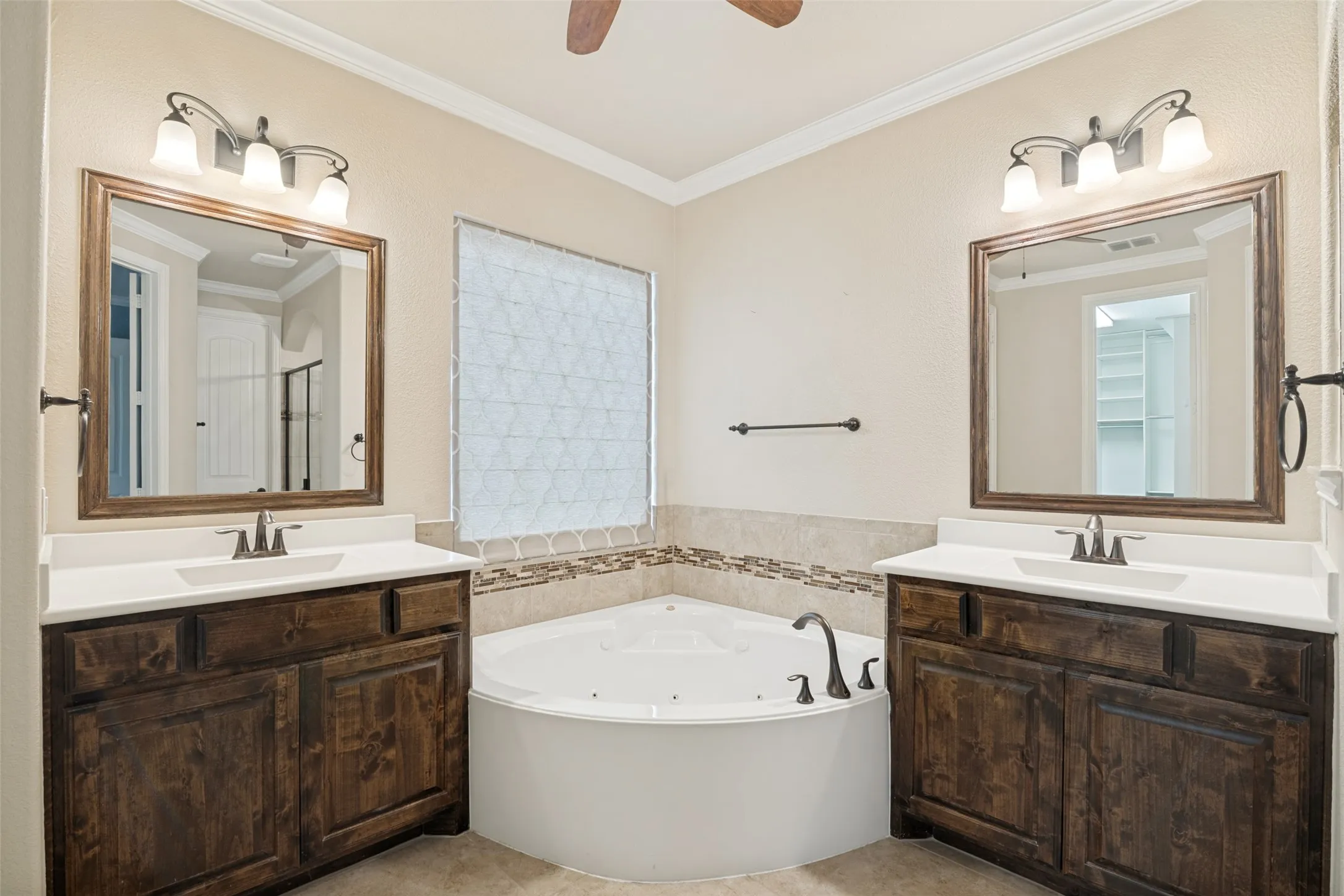Primary bath has large jetted tub and two vanities.