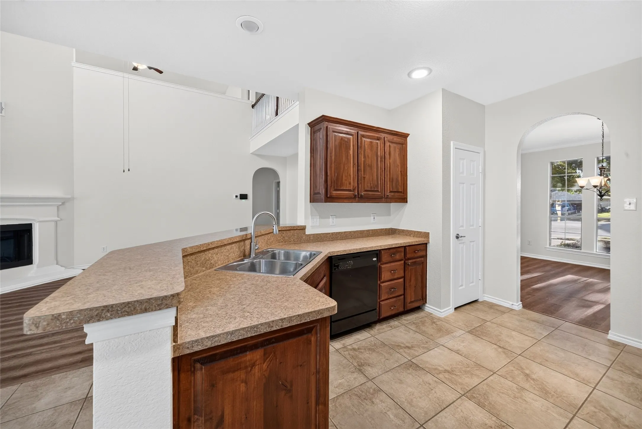 Kitchen with wood-finish cabinetry, double basin sink, and integrated dishwasher