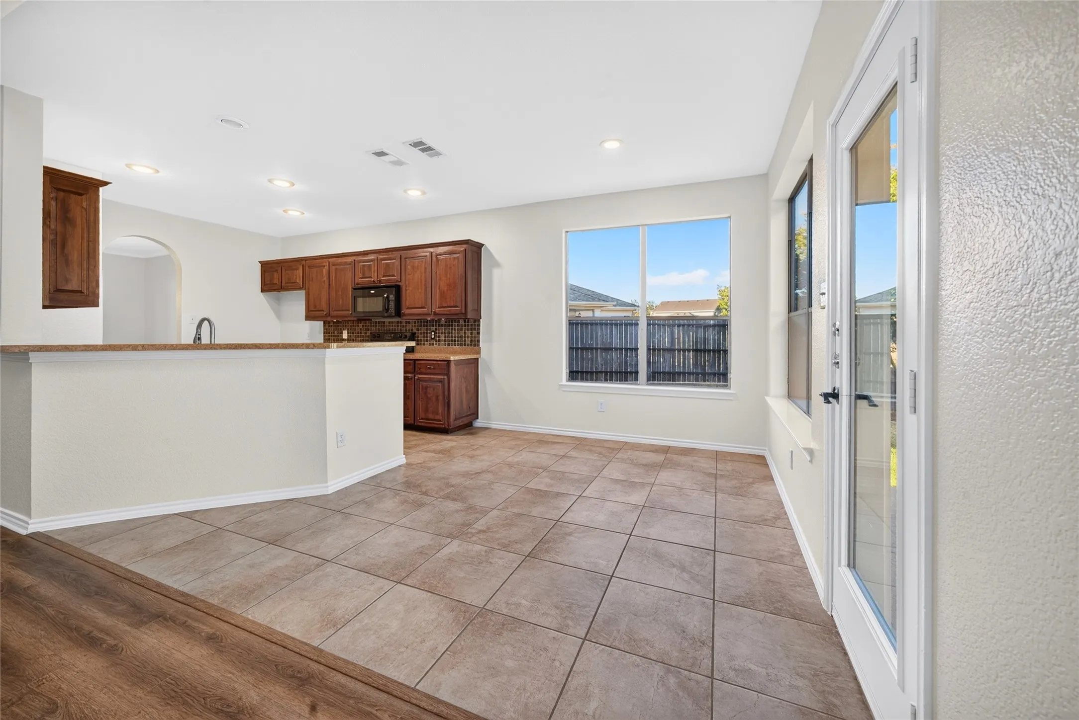 Kitchen featuring wood cabinetry, tiled backsplash, and built-in microwave