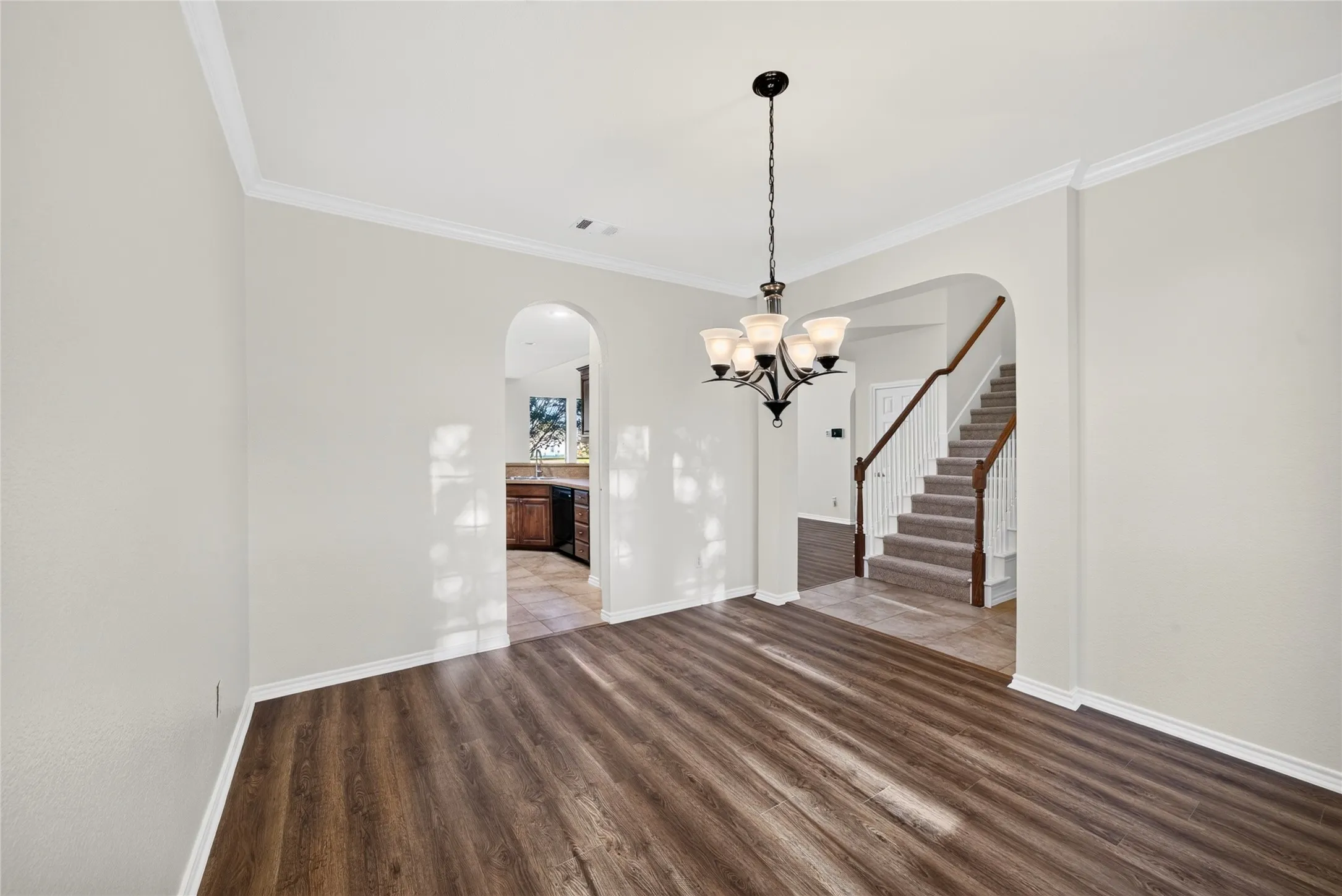 Wood-finish flooring with crown molding and a five-light chandelier