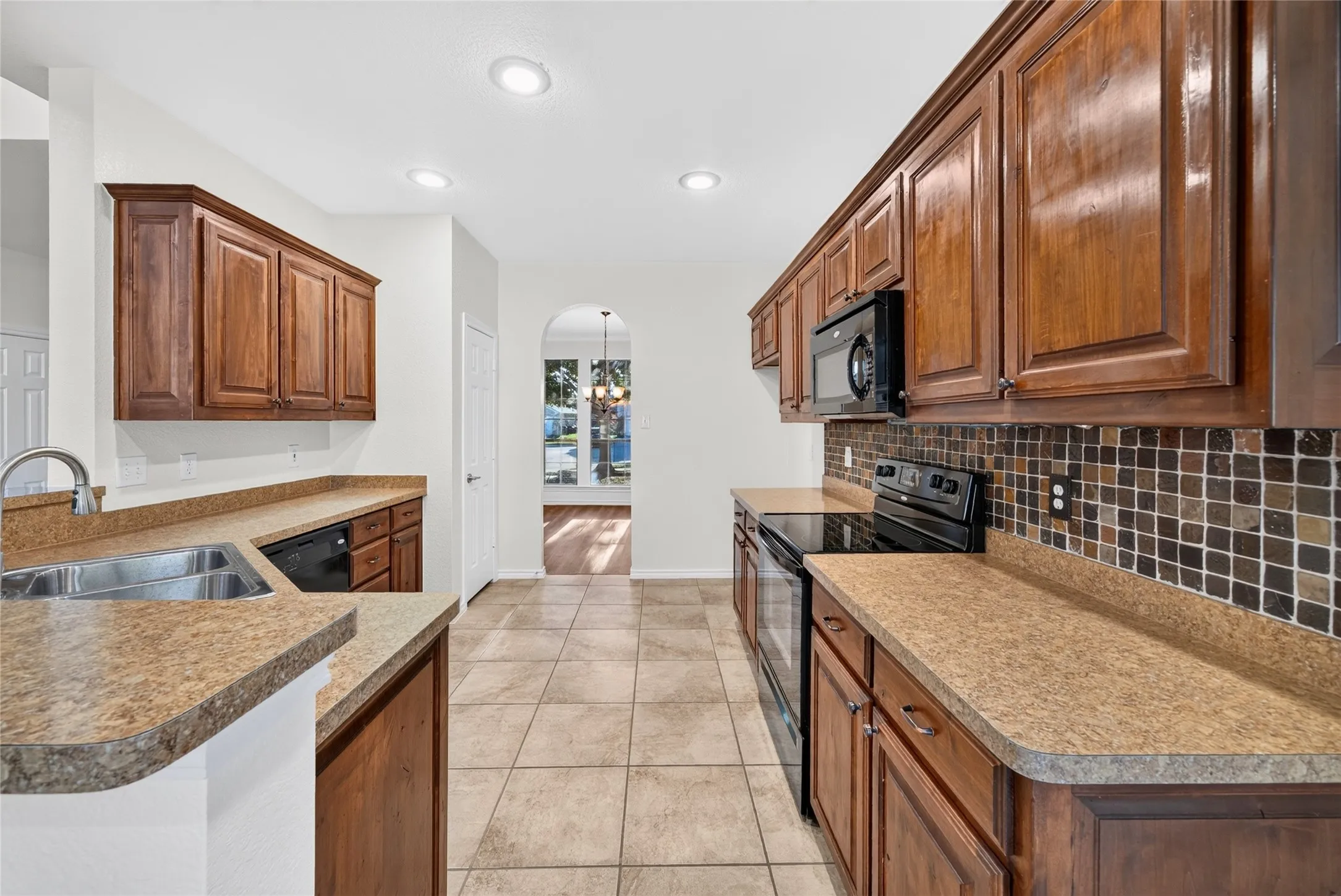 Kitchen featuring wood cabinetry, solid surface countertops, tile flooring, and a tile backsplash