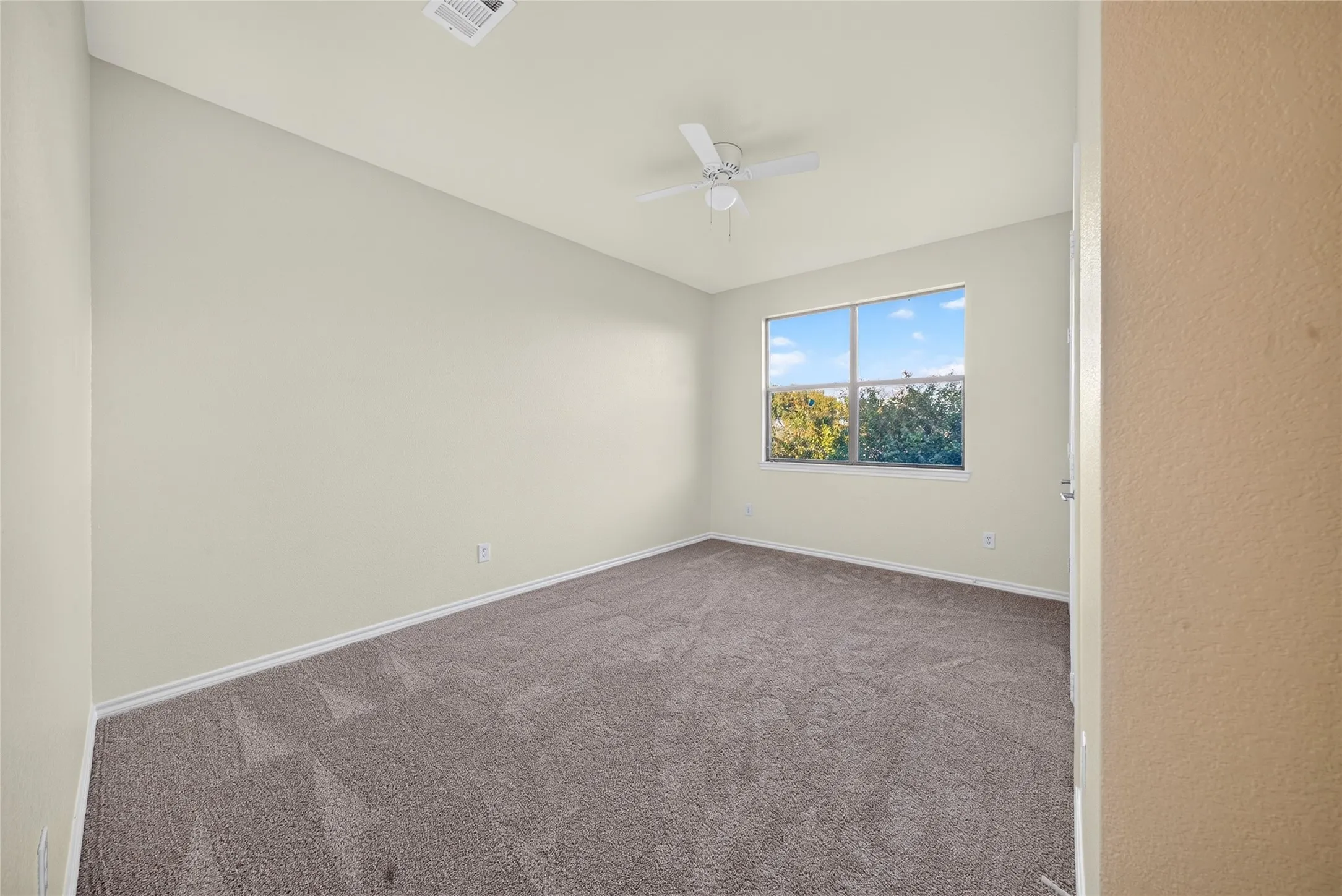 Window with exterior landscape, ceiling fan, and carpeted flooring