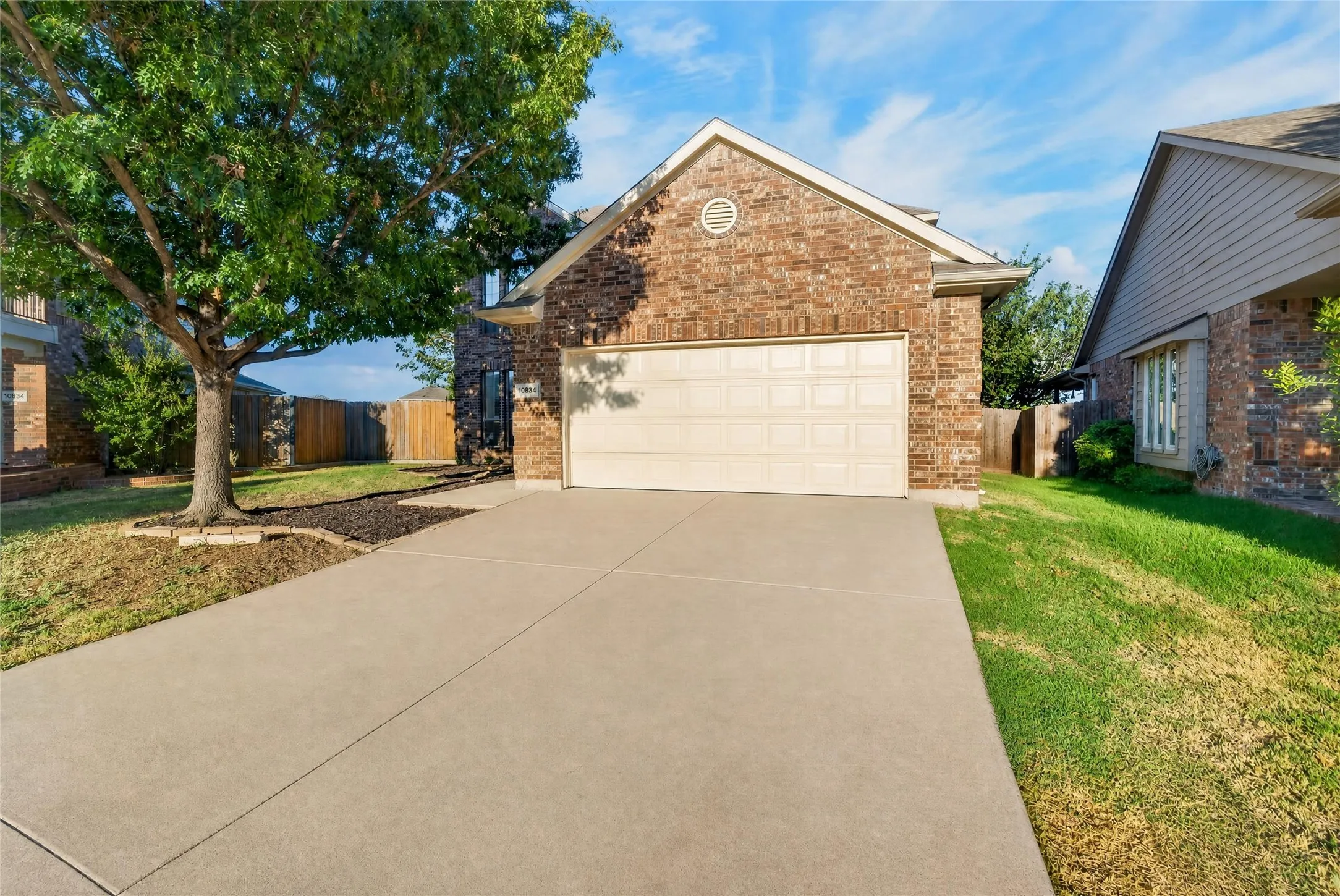 Brick exterior, two-car garage, concrete driveway, mature tree, established landscaping
