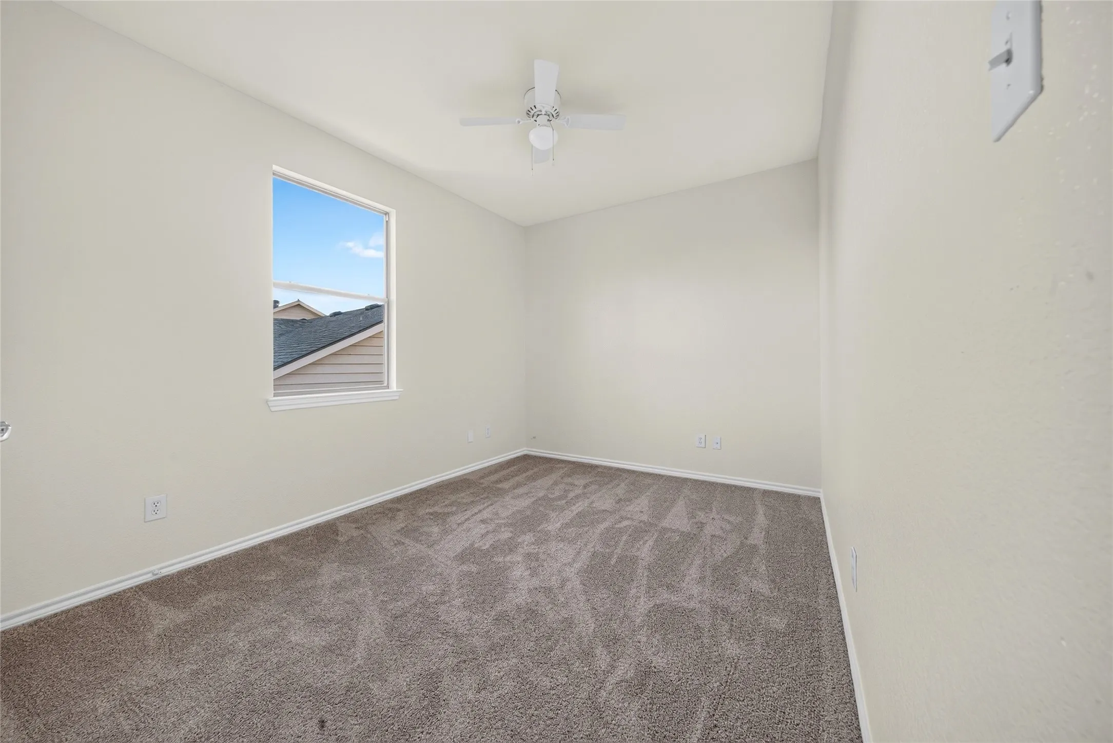 Carpeted room featuring a single window and a ceiling fan