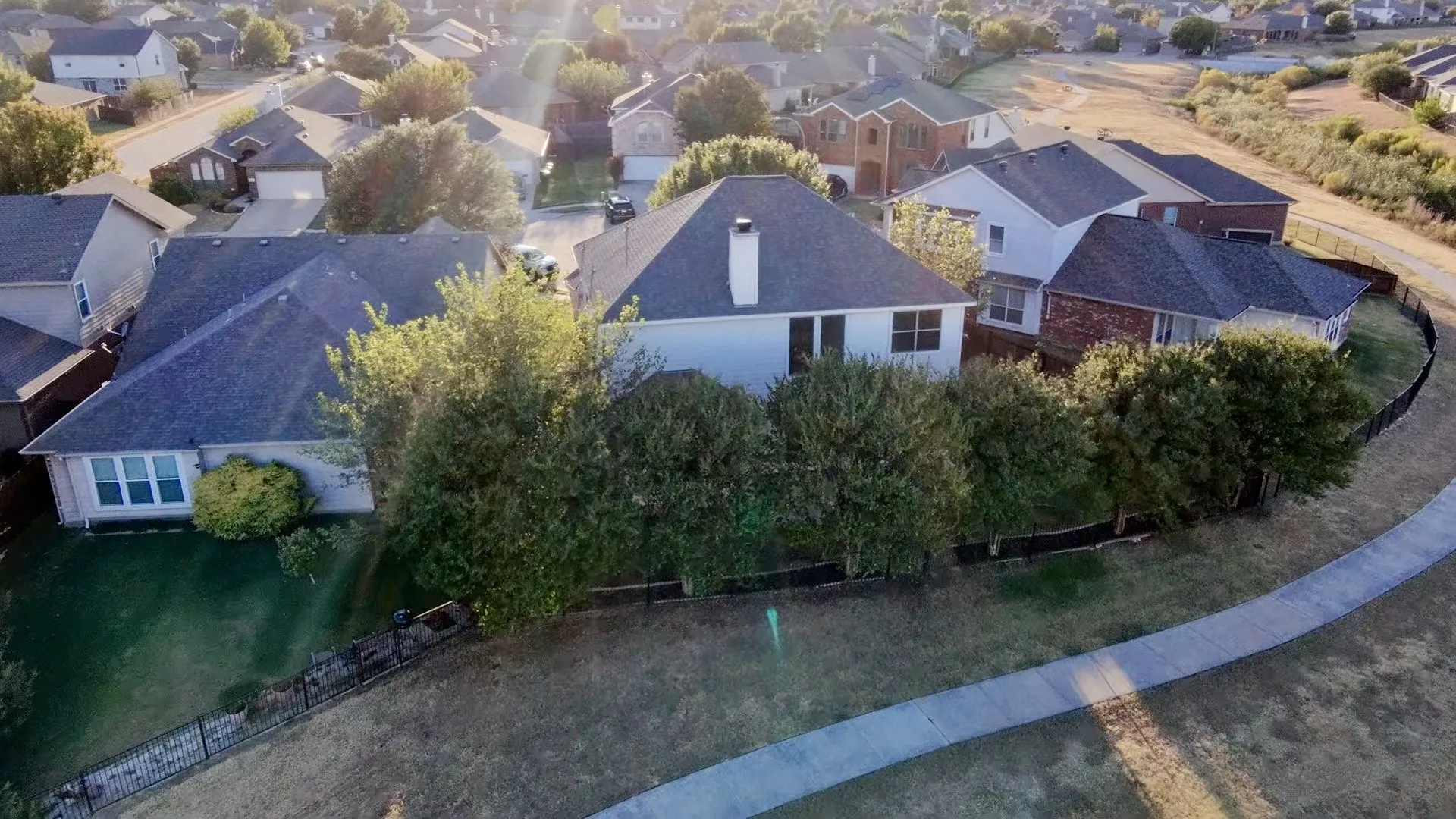 Shingle roof, mature landscaping, sidewalk, and fenced yard