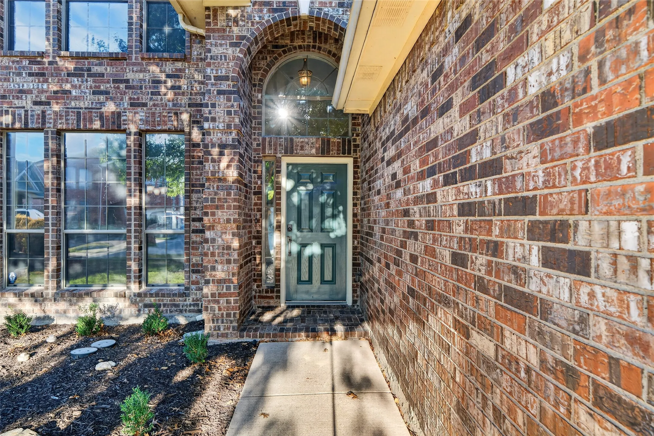 Brick exterior with a prominent arched entry, transom window, and multiple pane windows