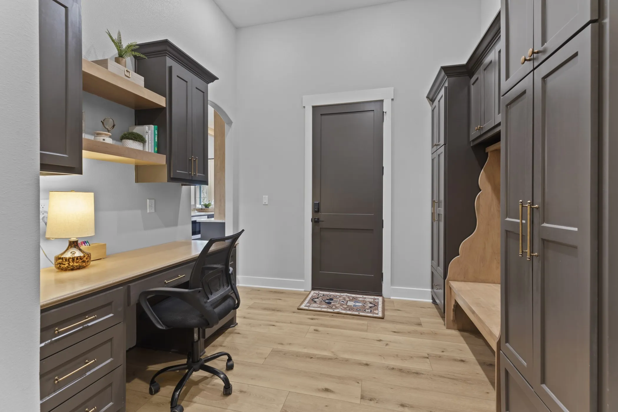 Built-in desk area with dark cabinetry, integrated open shelving, and light wood-finish countertop