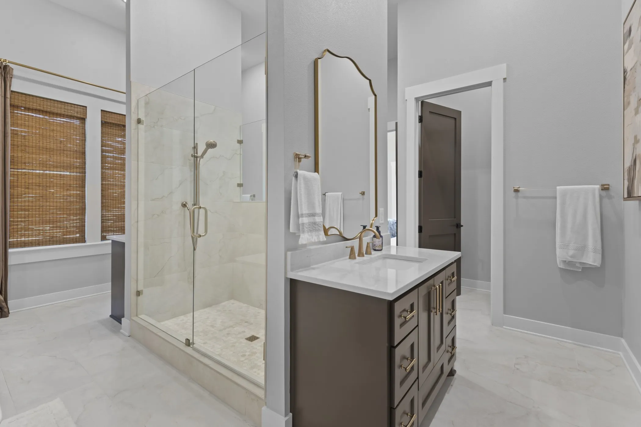 Glass-enclosed shower with marble-finish tile, a single vanity with quartz countertop, and white tile flooring