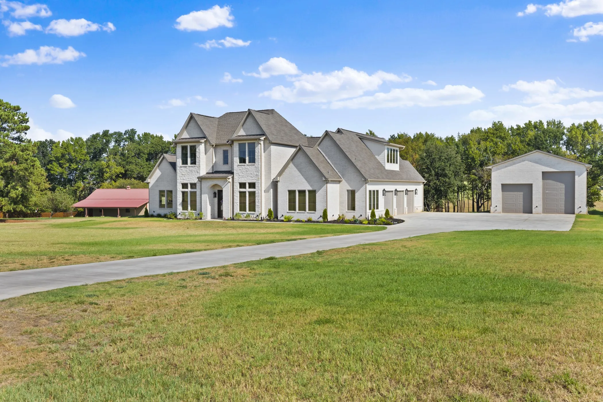 Stately residence with a light-colored brick exterior, prominent gables, and a dark roof
