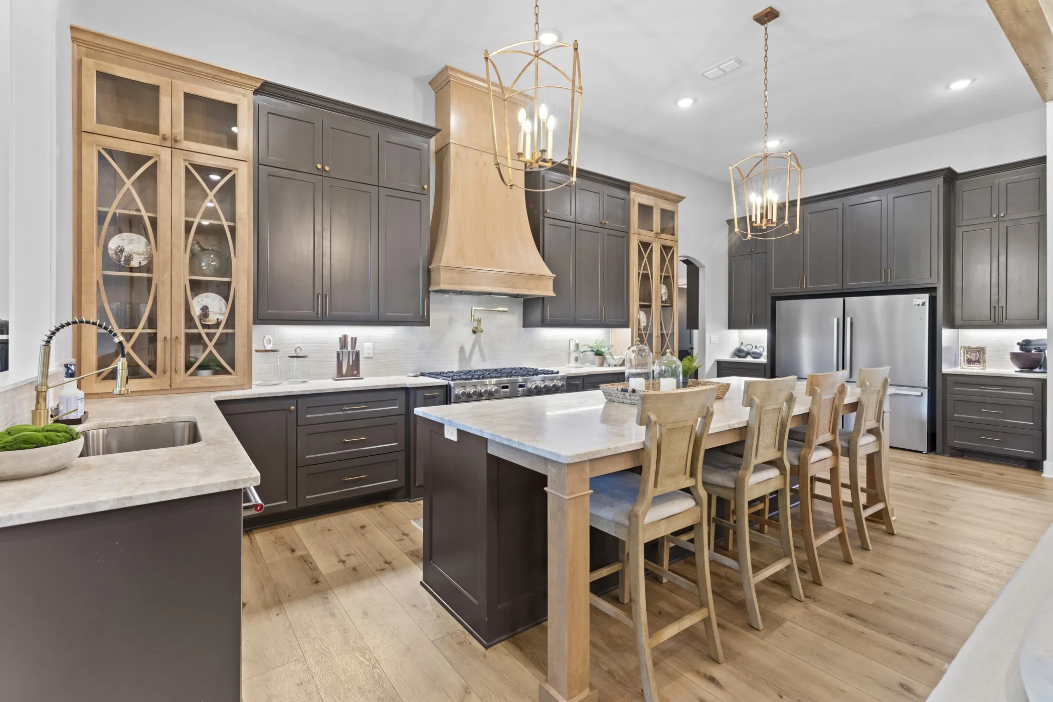 Kitchen featuring wood-finish flooring, two-tone cabinetry, stainless steel appliances, a center island with countertop seating, and recessed lighting