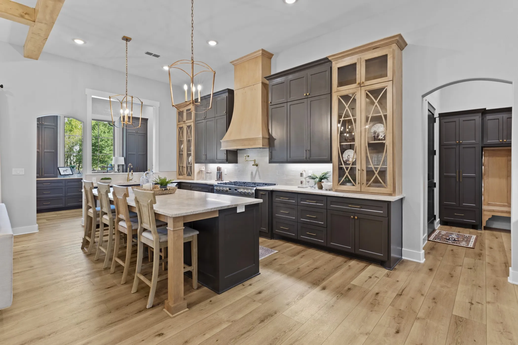 Spacious kitchen featuring a large island, wood-finish flooring, recessed lighting, and mixed-material cabinetry with display fronts