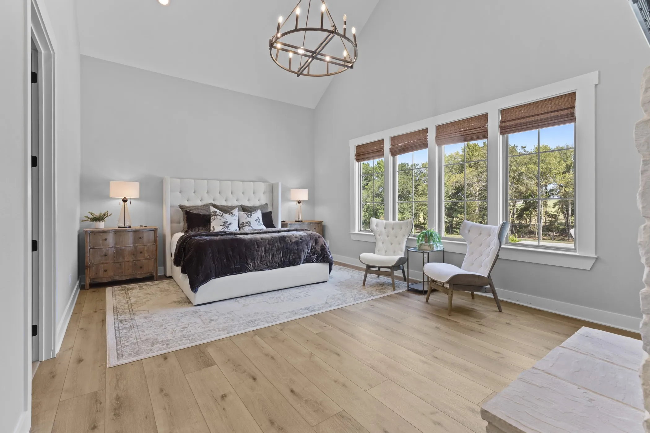 Vaulted ceiling with an open-cage chandelier, wood-finish flooring, and a wall of windows