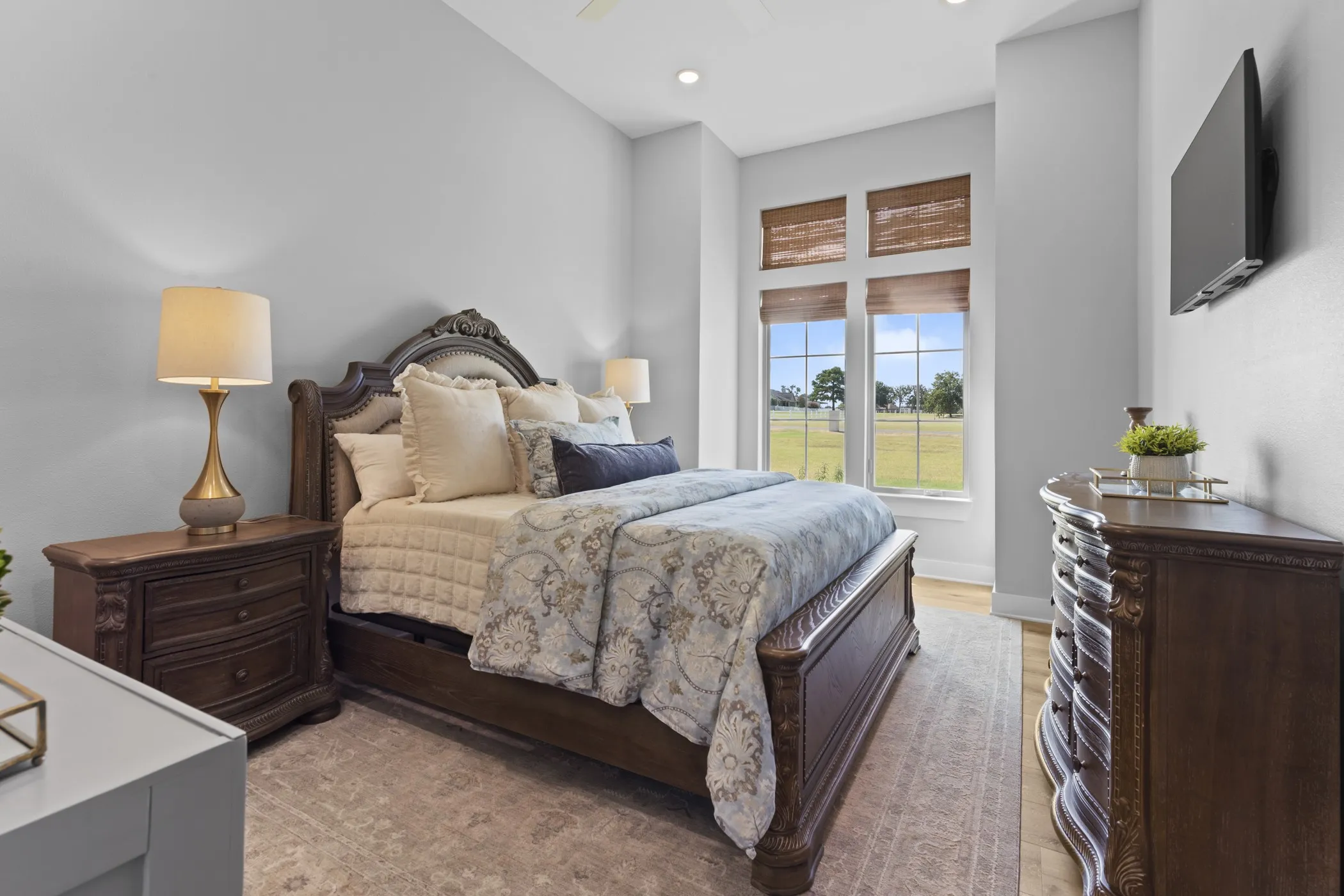 Recessed lighting, light wood-finish flooring, and multiple windows with woven window treatments