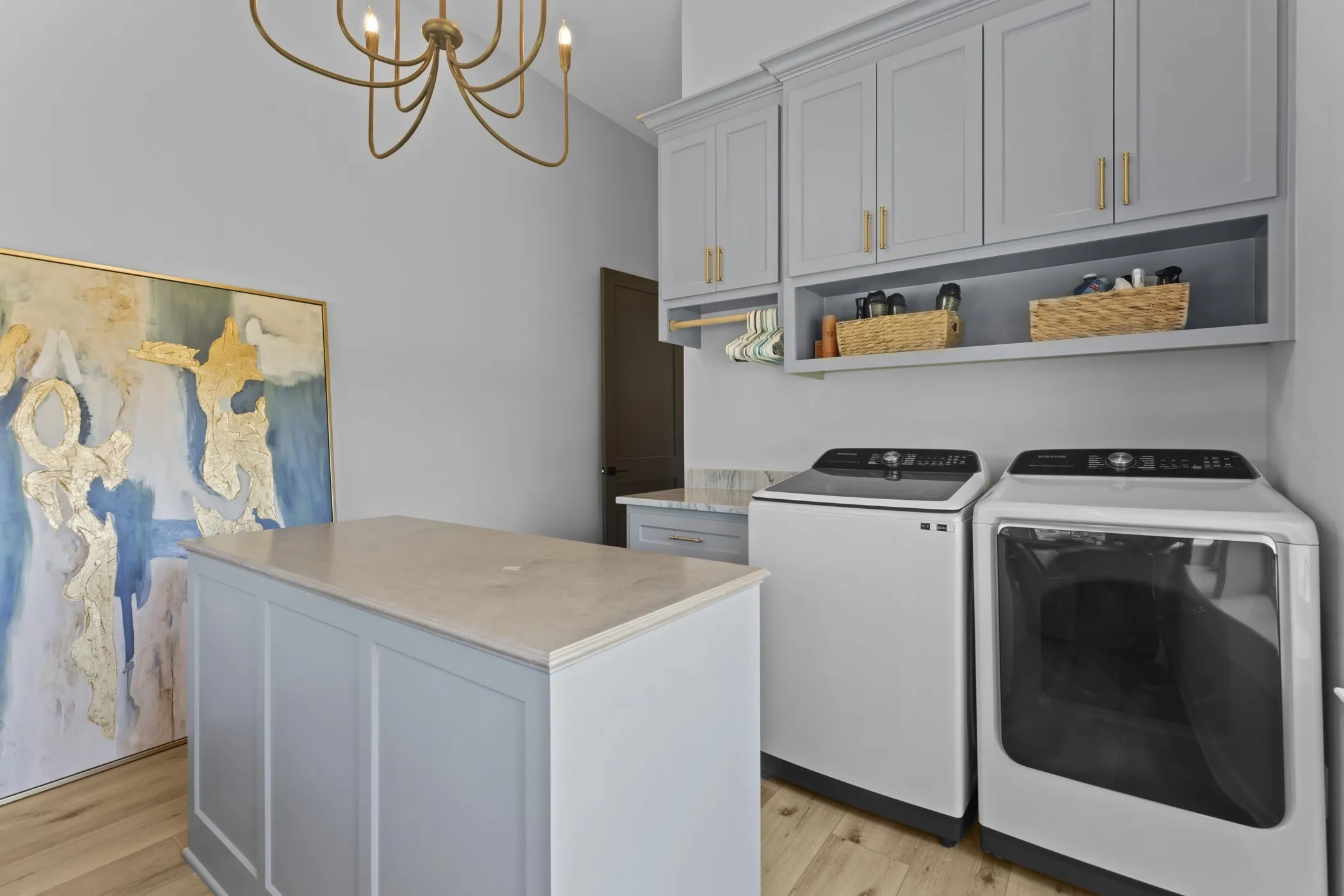 Laundry room with wood-finish flooring, built-in cabinetry, and a central island with a solid surface countertop