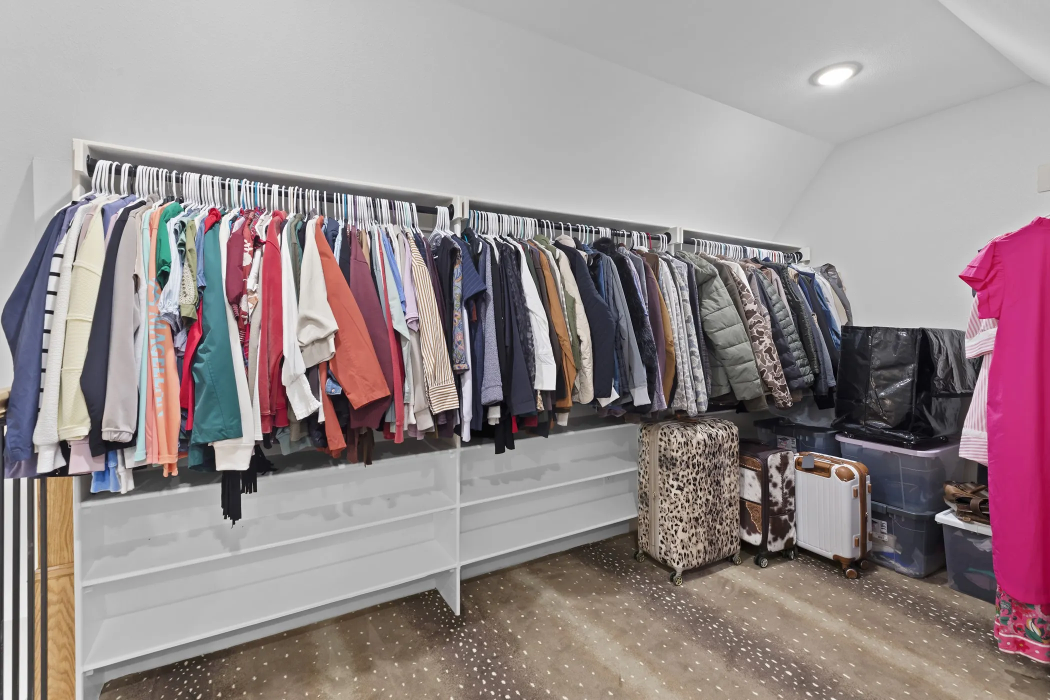 Recessed ceiling lighting, sloped ceiling, built-in shelving, and built-in clothes rods