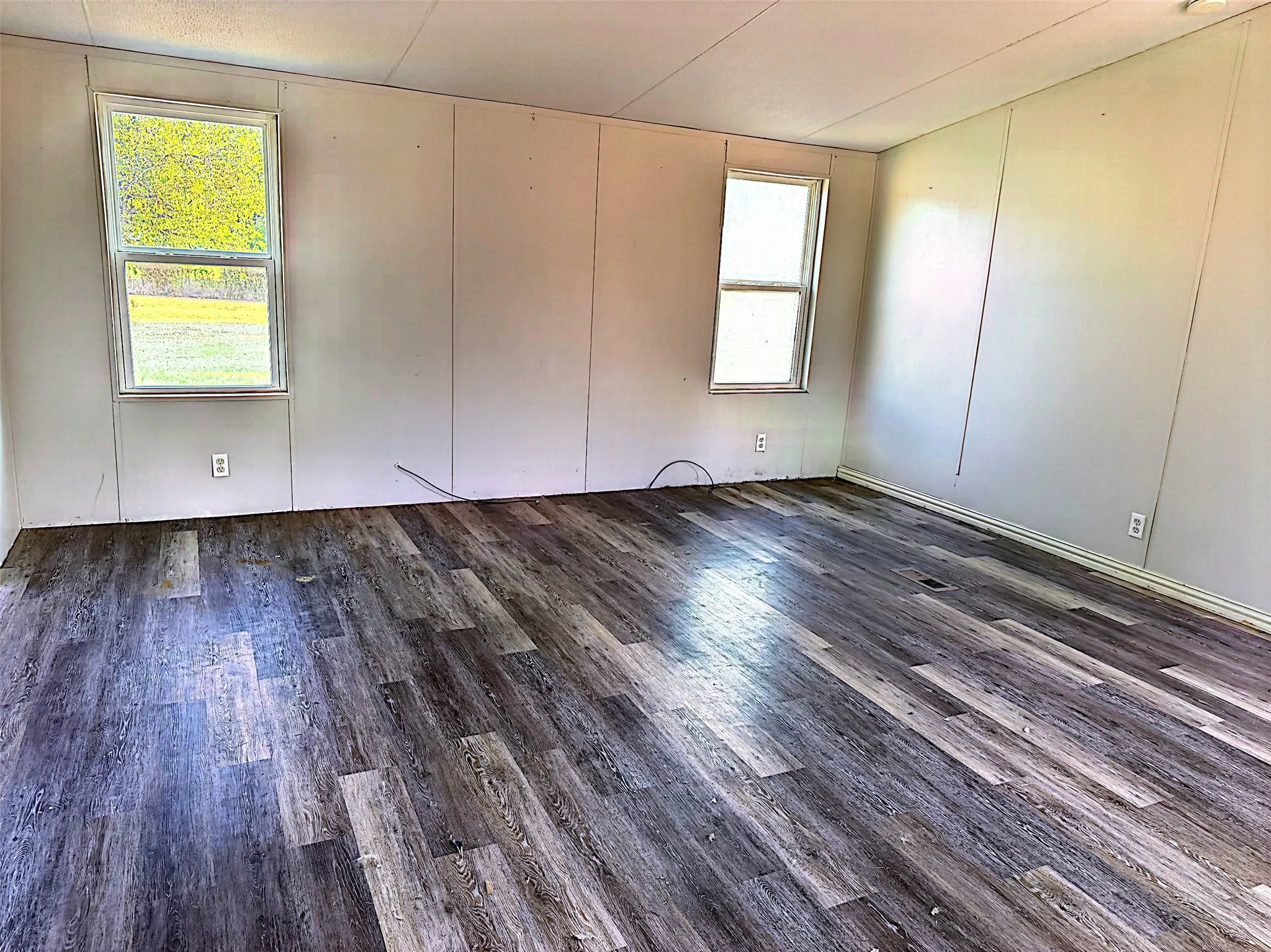 Wood-finish flooring throughout, complemented by light-toned wall paneling and multiple windows