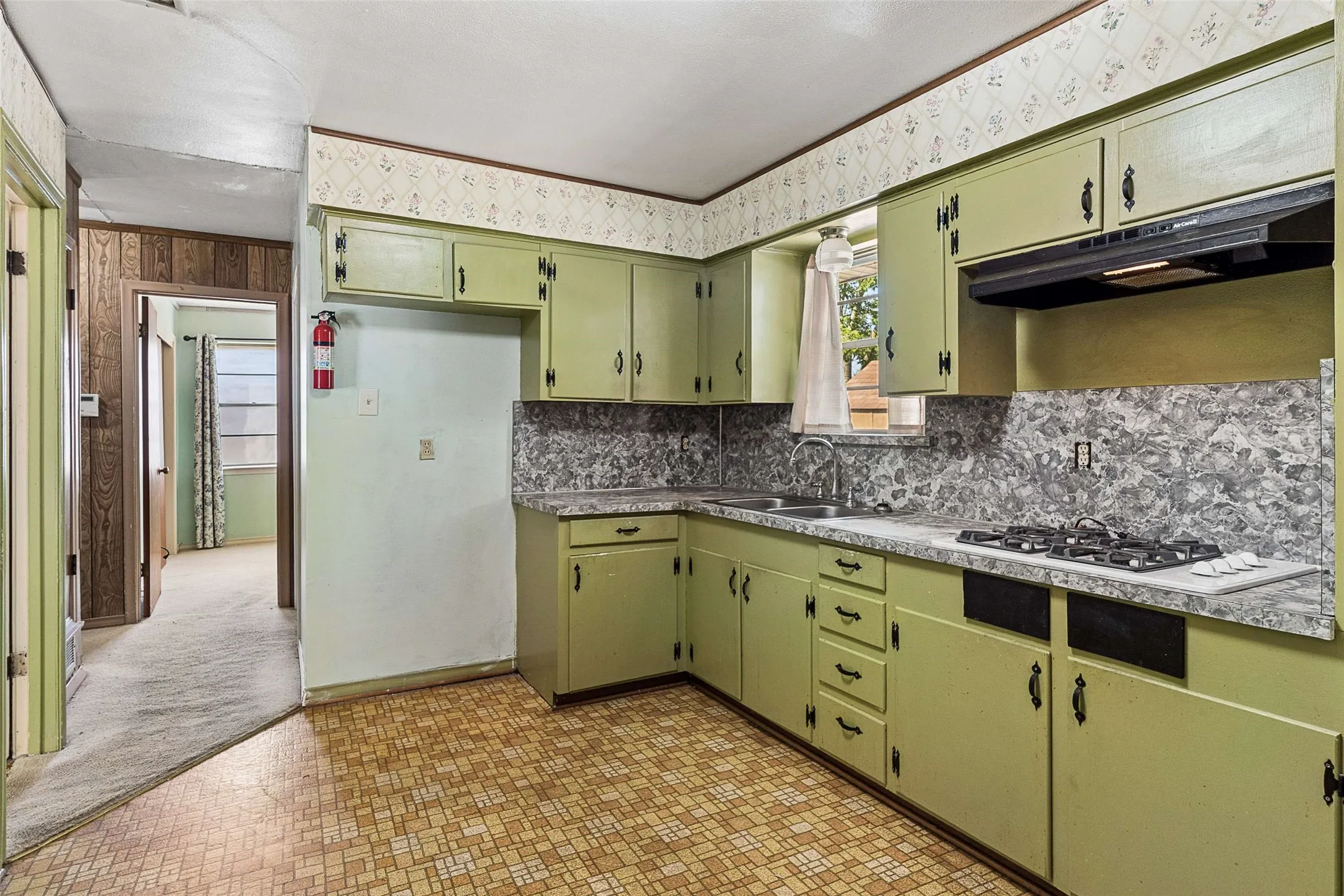 Kitchen featuring a gas range, dual basin sink, and ample cabinetry with decorative hardware