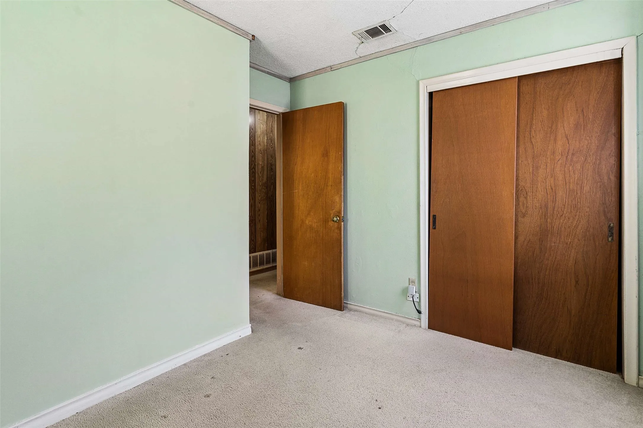 Neutral-toned wall-to-wall carpeting, wood-finish sliding closet doors, and a wood-finish interior door