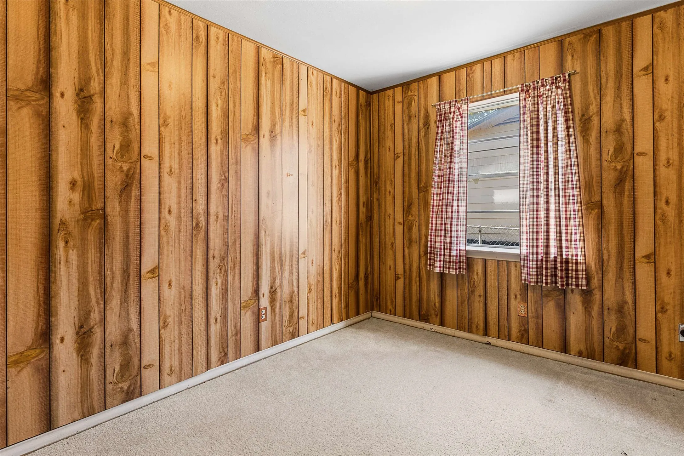 Wood-paneled walls with a window and carpeted flooring
