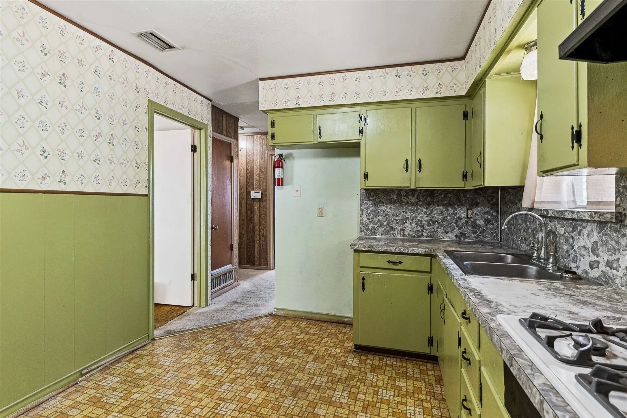 Kitchen featuring a double basin sink, gas range, and green cabinetry