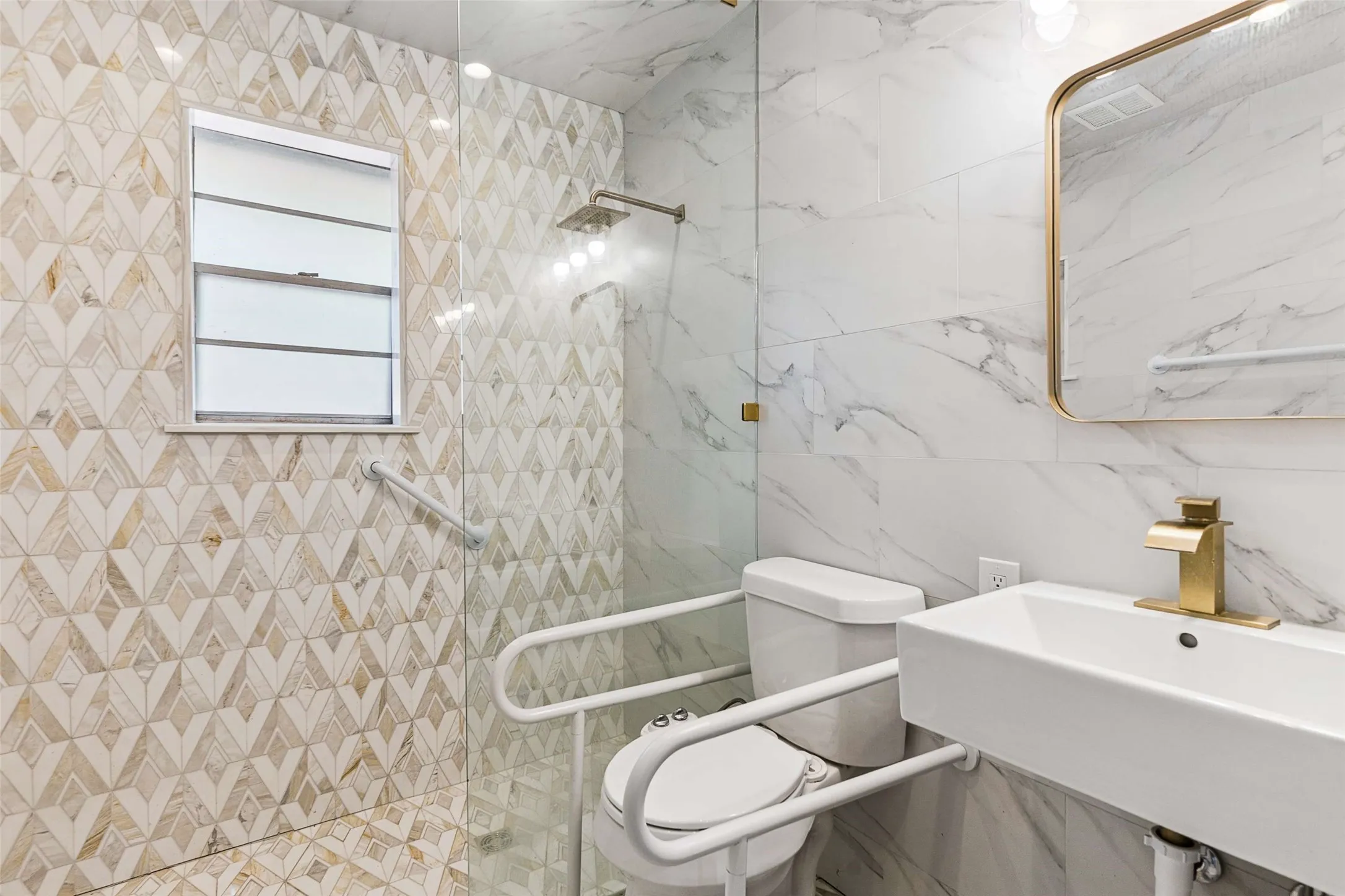 Modern bathroom featuring a wall-mounted rectangular sink, gold-tone faucet, and an illuminated mirror with a gold-tone frame