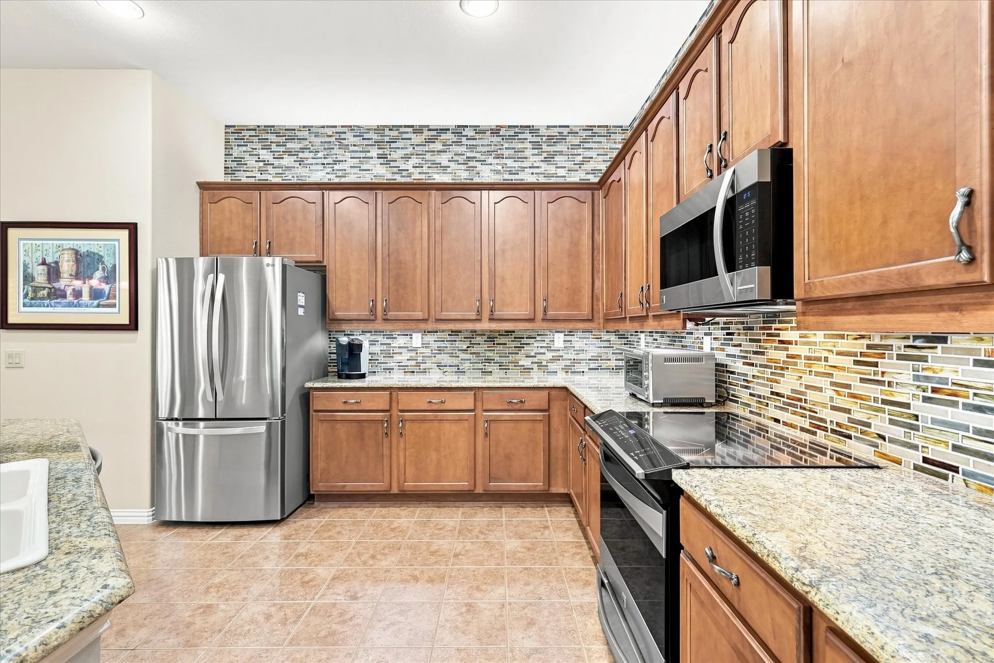 Warm wood cabinetry, tile flooring, and granite countertops with a multi-tone tile backsplash